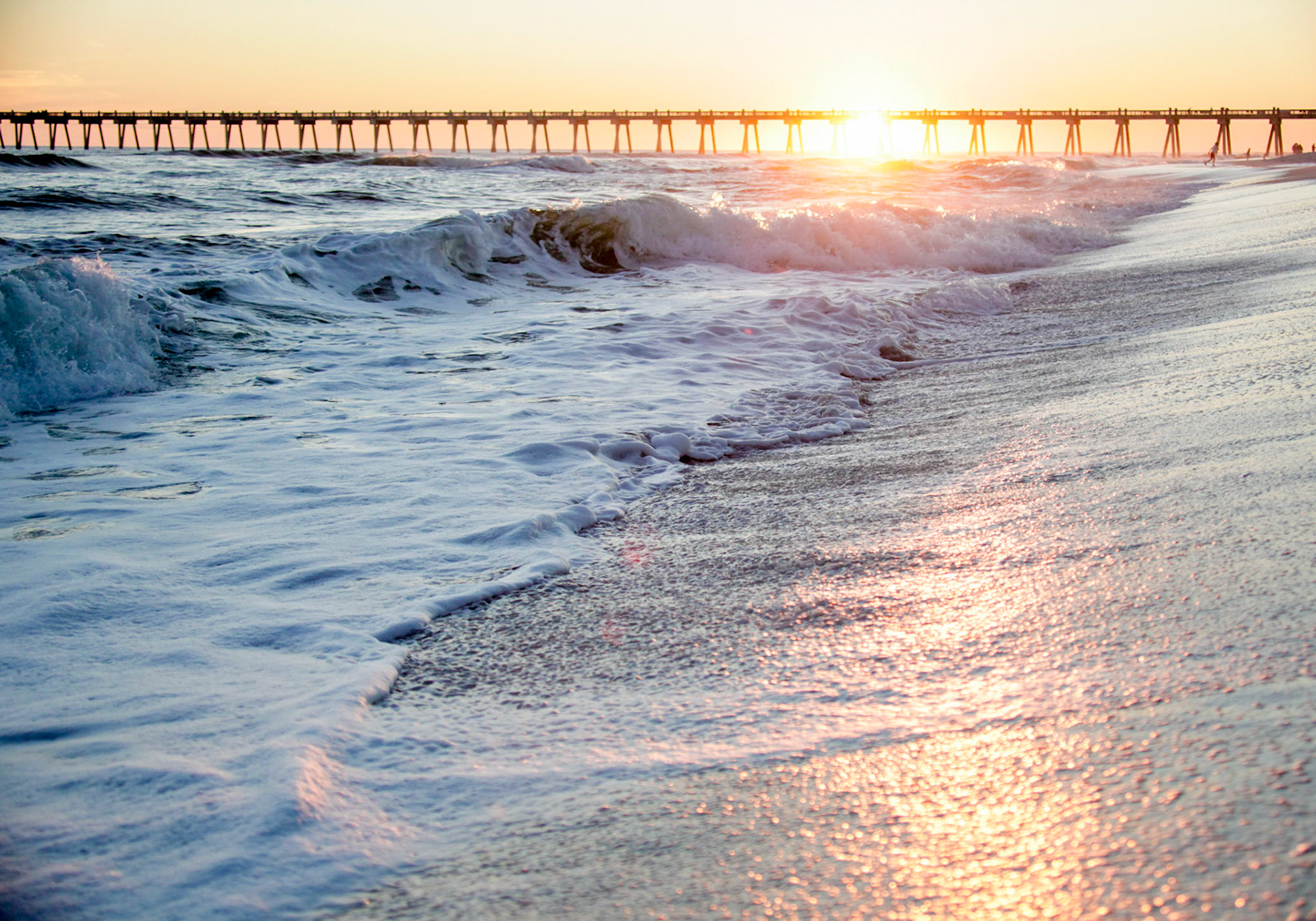 Frothy tide mixing on sunset shore...dark pier in the distance