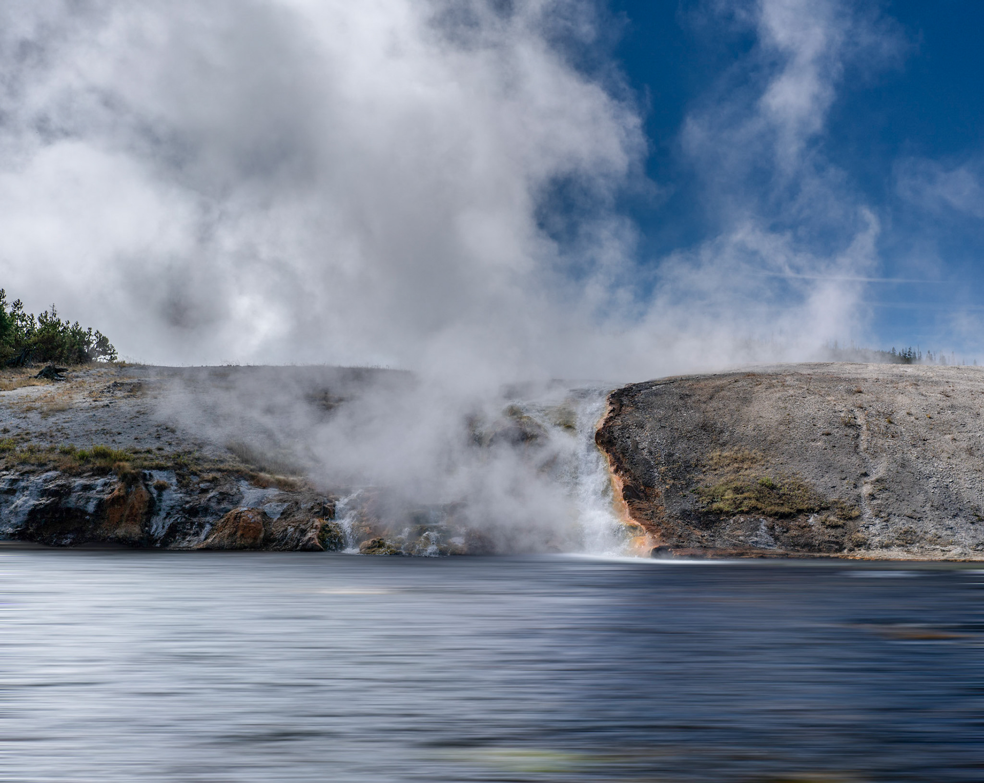 Steam rising from the geysers flow into firehole river from the grand prismatic springs