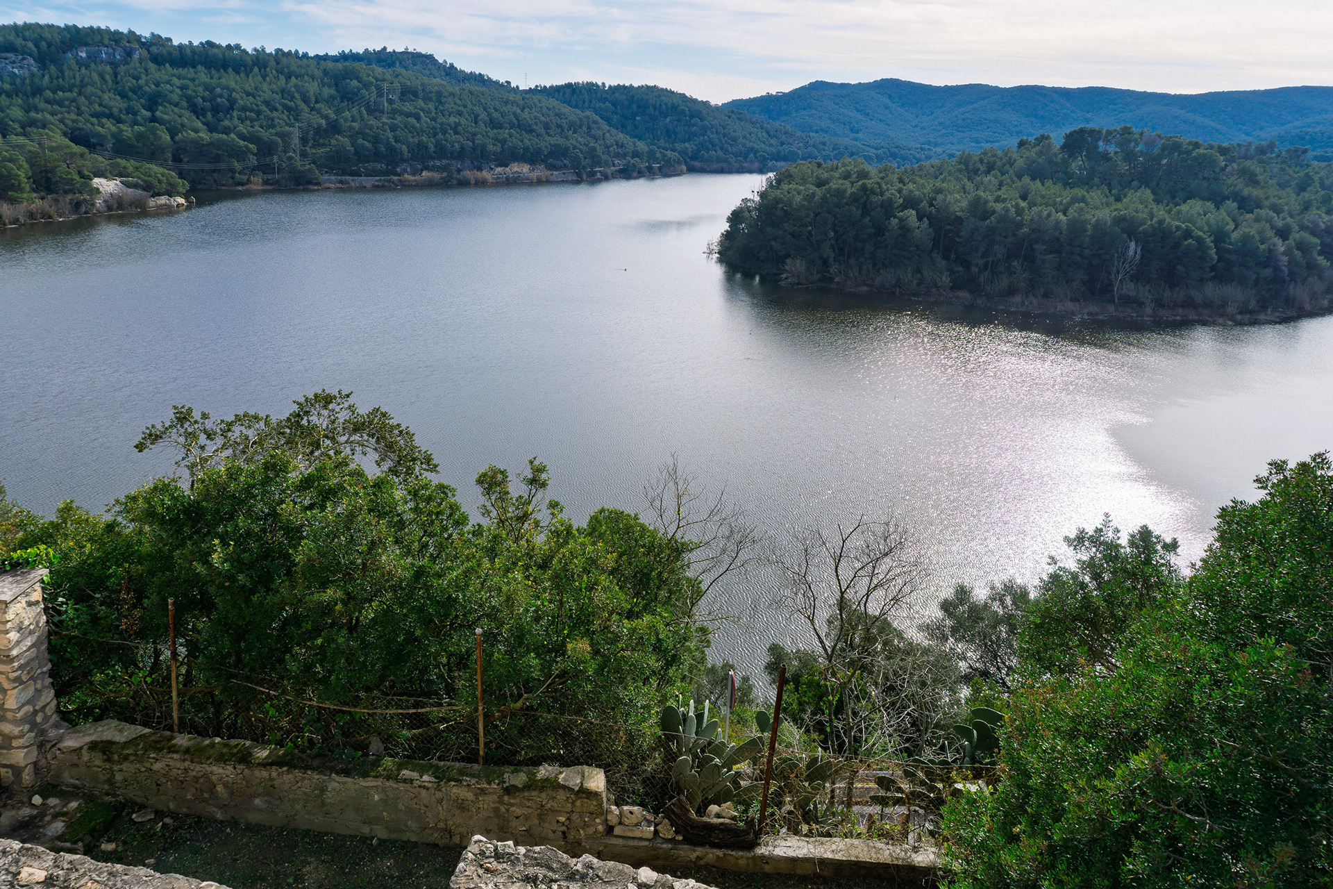 Where water meets history: Foix Reservoir framed by Castellet's medieval stones.