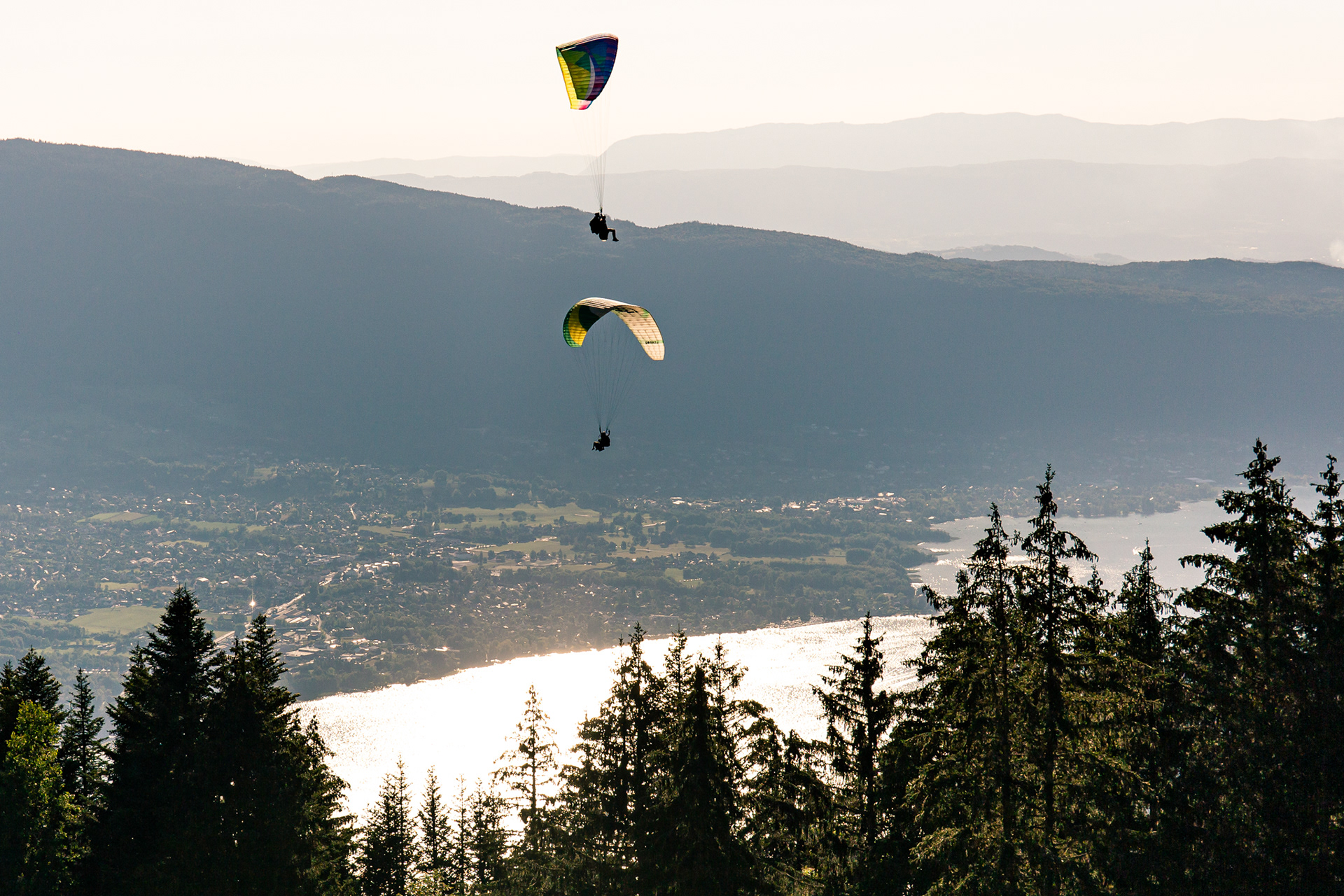 Hundreds of paragliders gliding along the steep cliffs and rock faces.