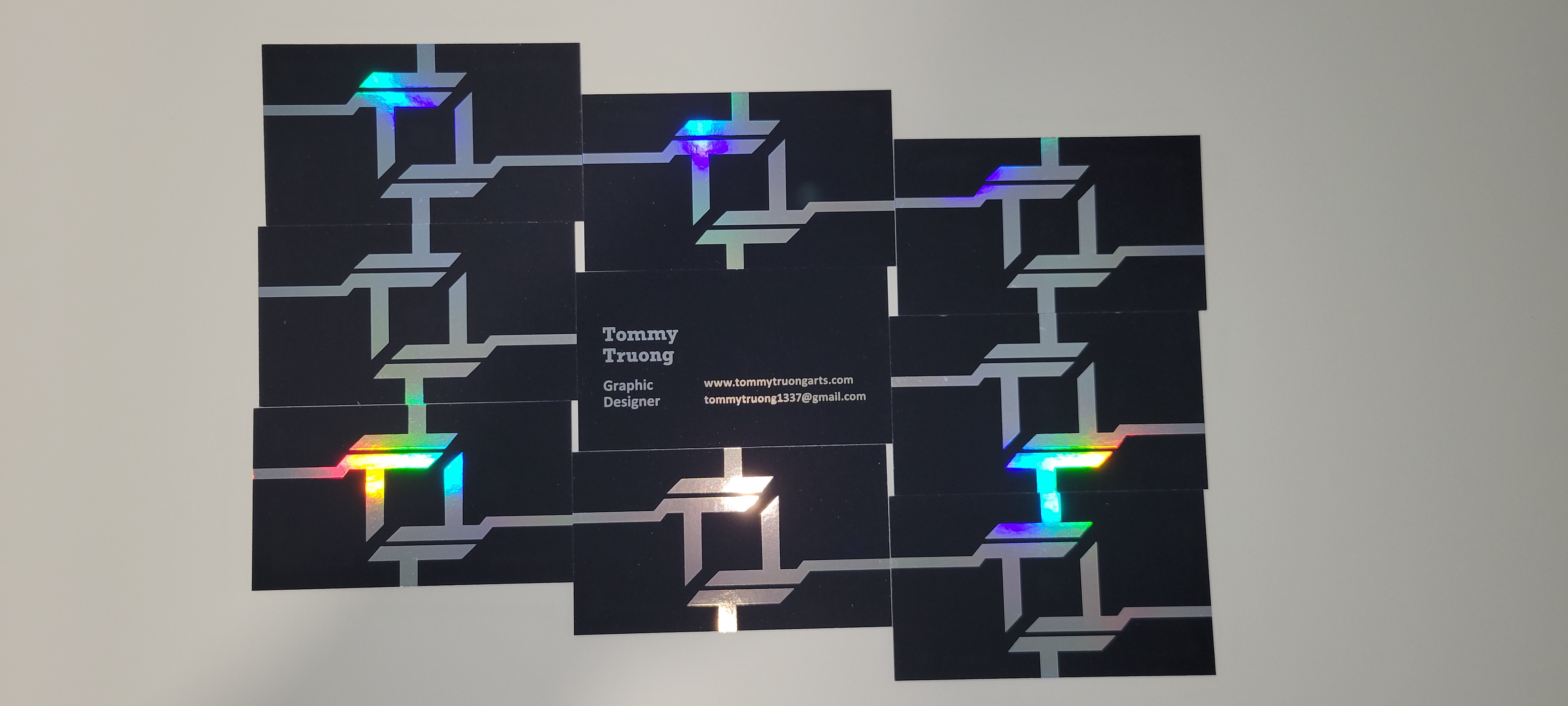 A depiction of the front and back of my business cards. The rainbow of colors on display is due to the holographic foil these cards have.