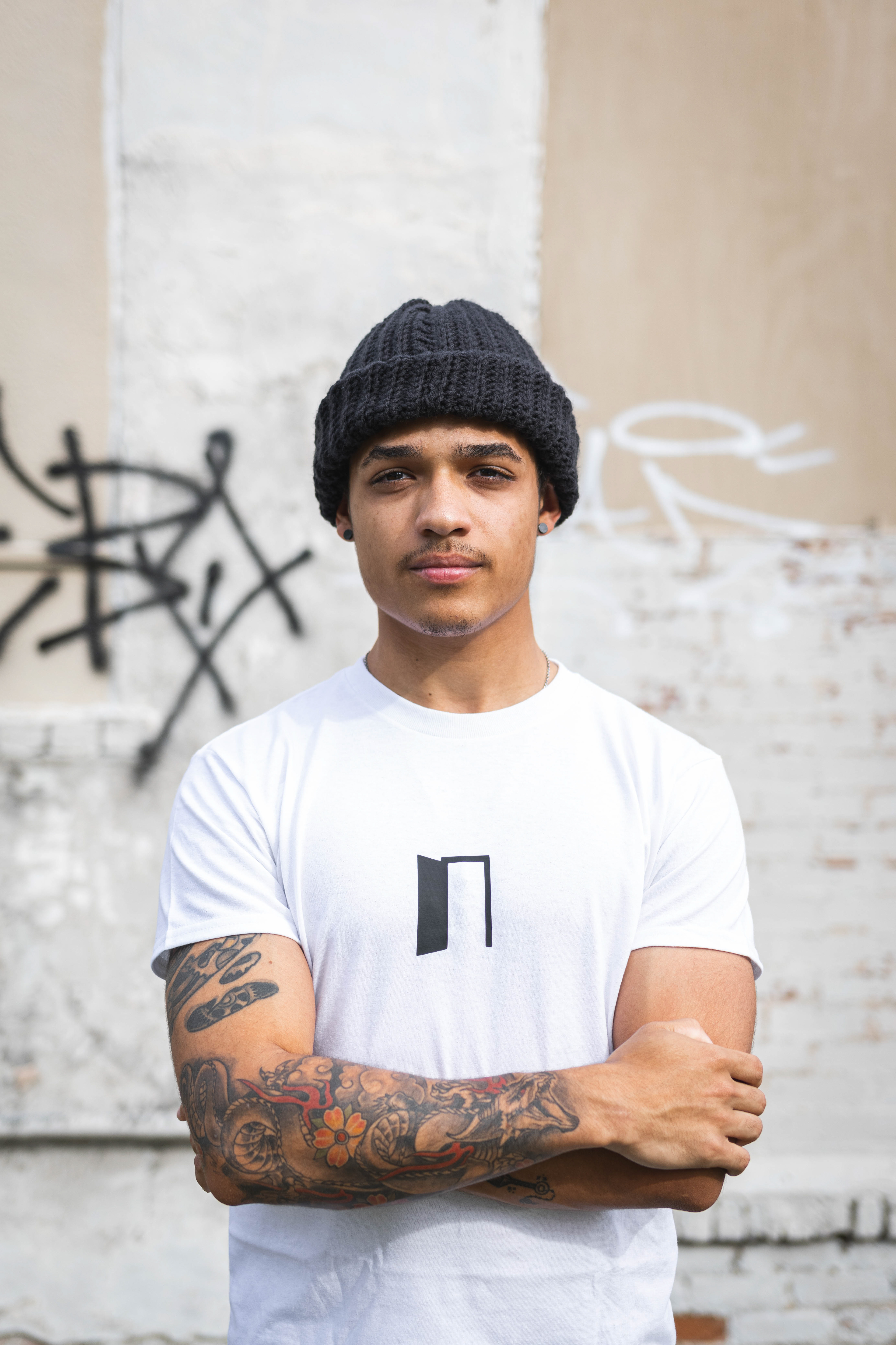 @brogan_the_first1 | Portrait photography outdoor in front of graffiti, black beanie and white graphic t-shirt by @my.insideoutside