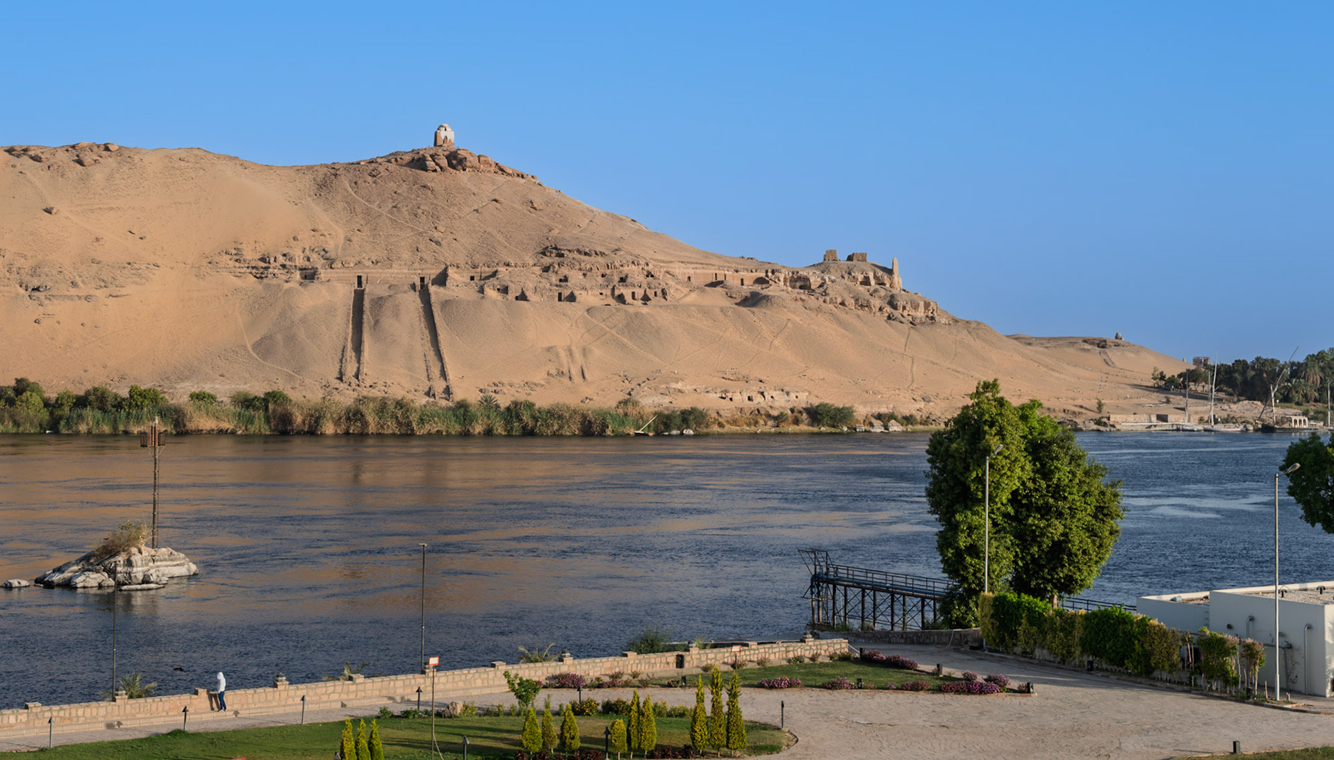 View from hotel across the Nile to Qubbet el-Hawa (Dome of the Wind). 100 rock cut tombs for nobles primarily from Middle Kingdom, also Old Kingdom.