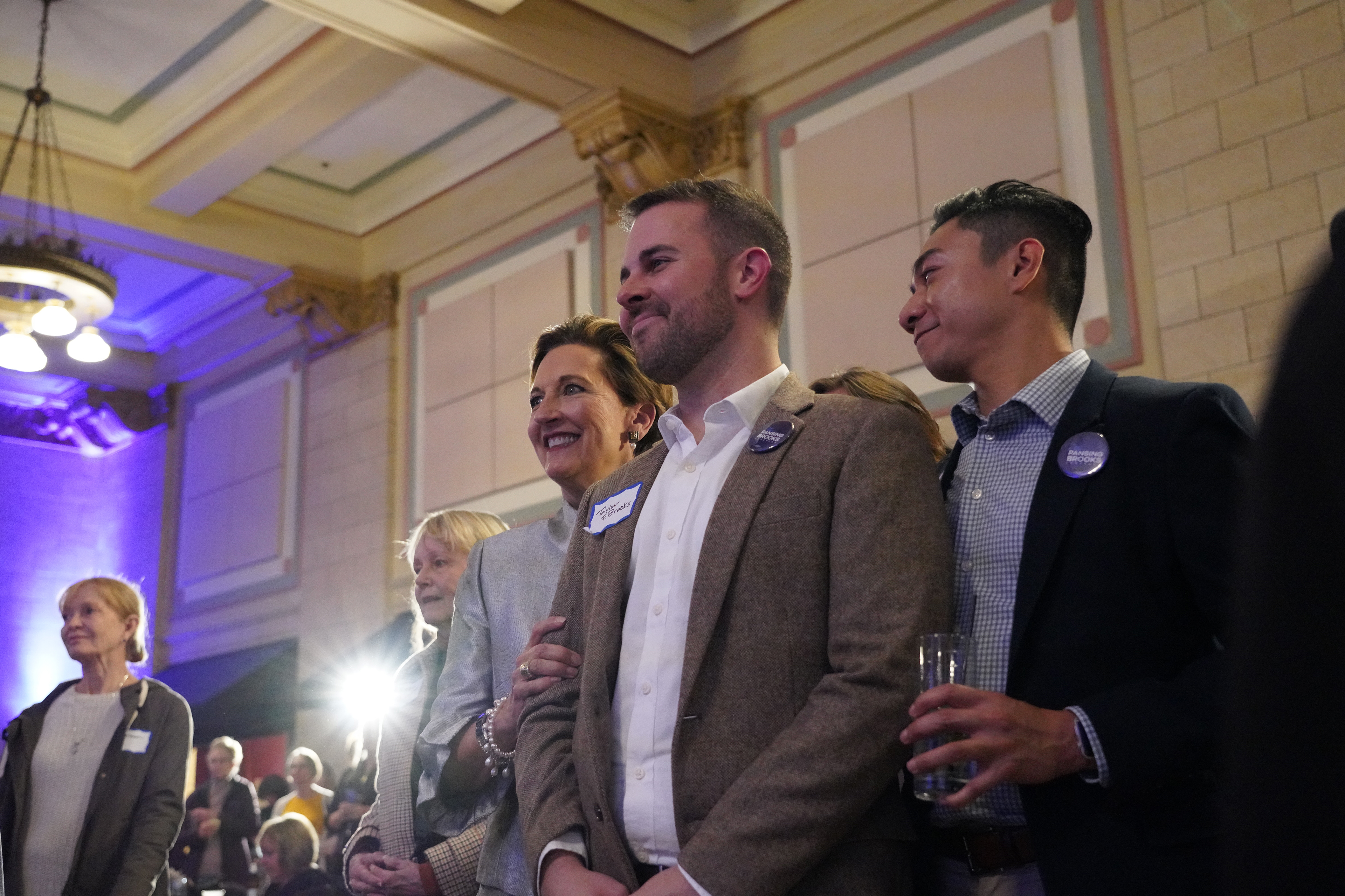 Patty Pansing Brooks stands next to her son Taylor Brooks and his partner Greg Rafal as The Lincoln Queer Choir takes the stage during her election night party at Lincoln Station Great Hall on Nov. 8, 2022. (Nebraska News Service / Naomi Delkamiller)
