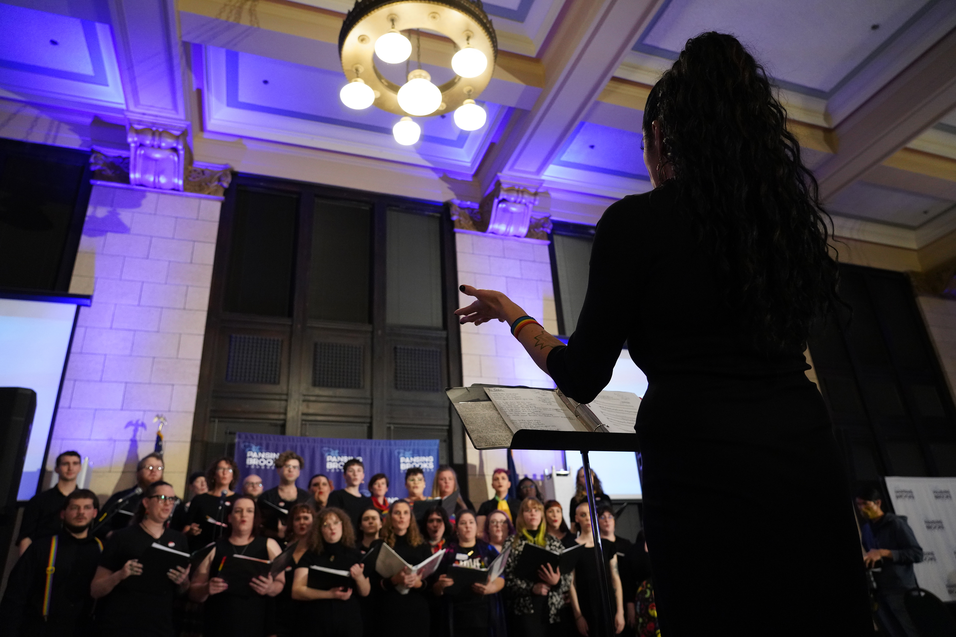 Lincoln Queer Choir Director Juju Tyner leads the choir as they perform at Patty Pansing Brooks' election night party at Lincoln Station Great Hall on Nov. 8, 2022. (Nebraska News Service / Naomi Delkamiller)