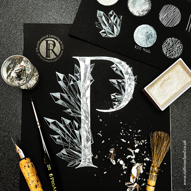 Lettering Artist London UK Ruth Rowland © Photo of gilded ice crystal P on desktop using imitation silver metal leaf with pen, brushes and metallic watercolours