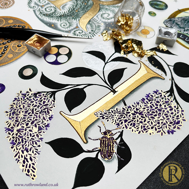 Lettering Artist UK London Ruth Rowland - Capital Letter I decorative initial inspired by novel Practical Magic with lilacs and beetle illustration. Photo of worksheet with gold and silver paint, gold leaf and brush