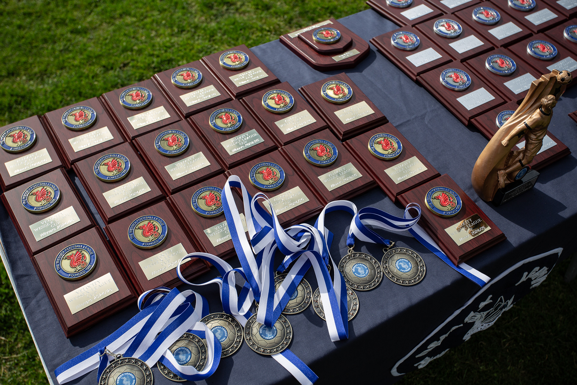 Winners medals for the Wessex League Cup final, arranged with a trophy on a table.
