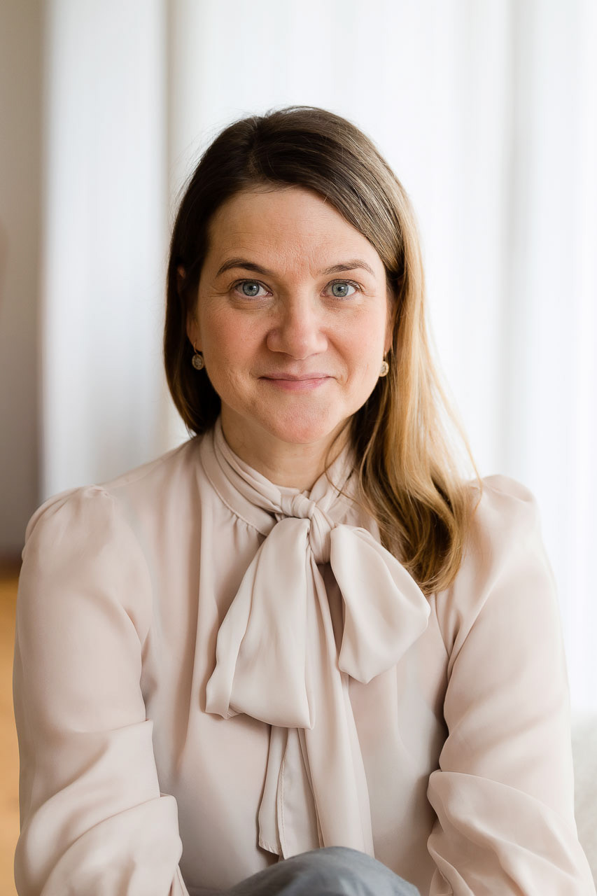 Authentisches Porträt einer Frau in cremefarbener Bluse, ideal für feminine Business-Fotografie