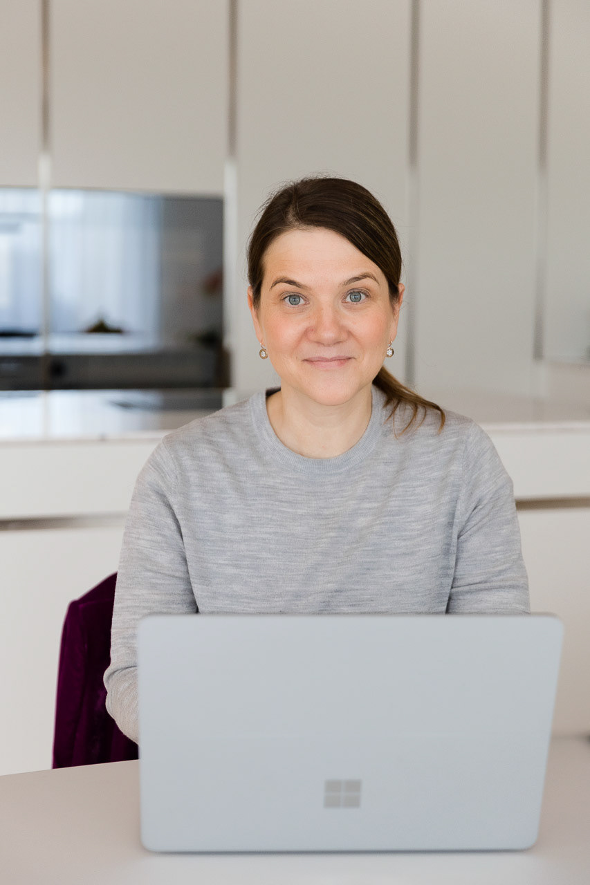 Professionelles Porträt einer Frau mit Laptop in moderner, heller Umgebung, perfekt für Business-Darstellung