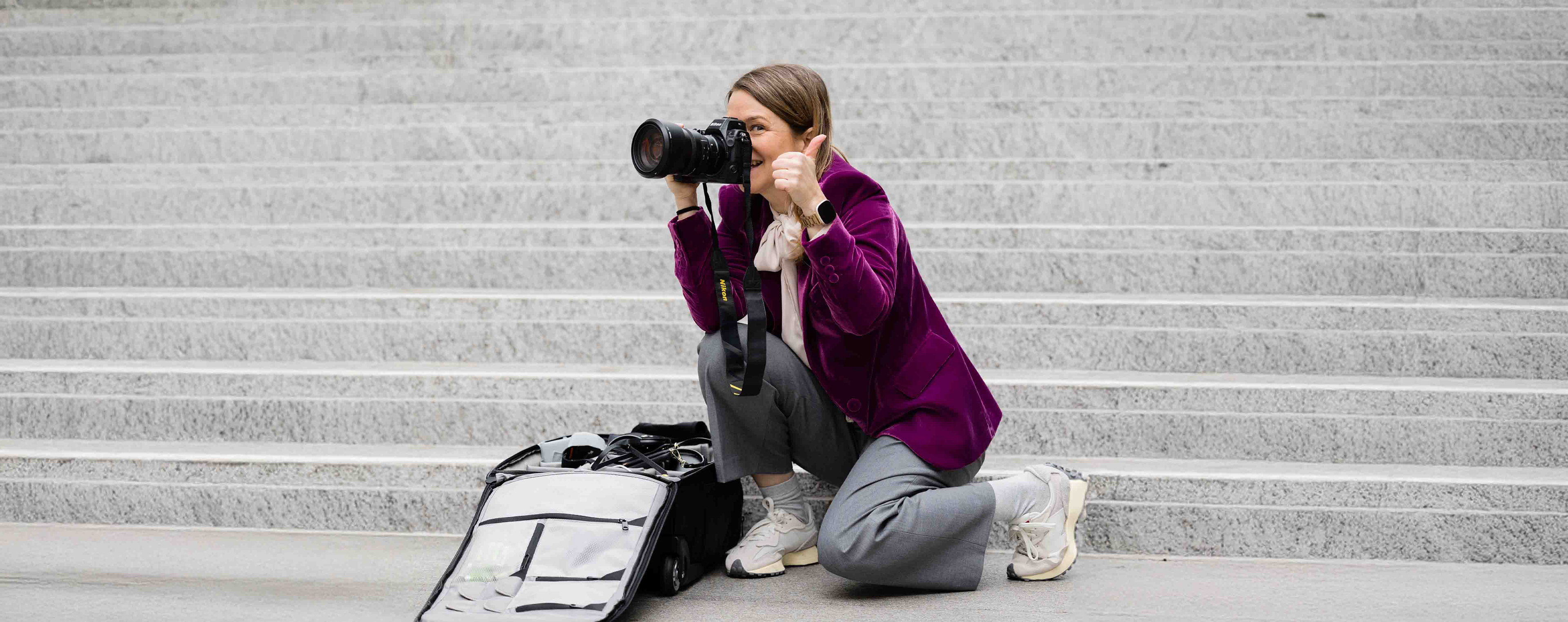 Kreative Fotografin bei der Arbeit, kniend auf Treppenstufen mit Kamera in der Hand. Ideales Bild für Personal Branding