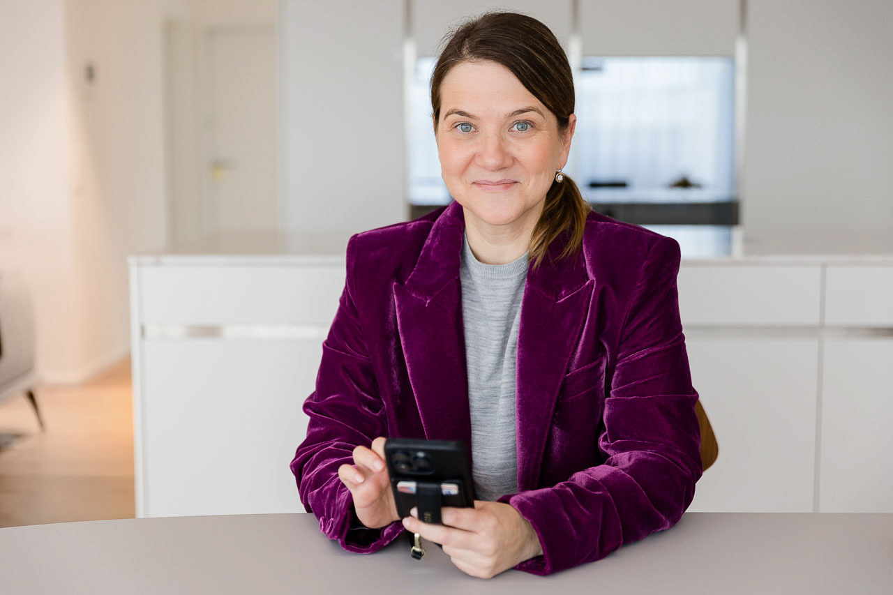 Porträt einer kreativen Unternehmerin in violettem Blazer mit Smartphone, ideal für modernes Branding