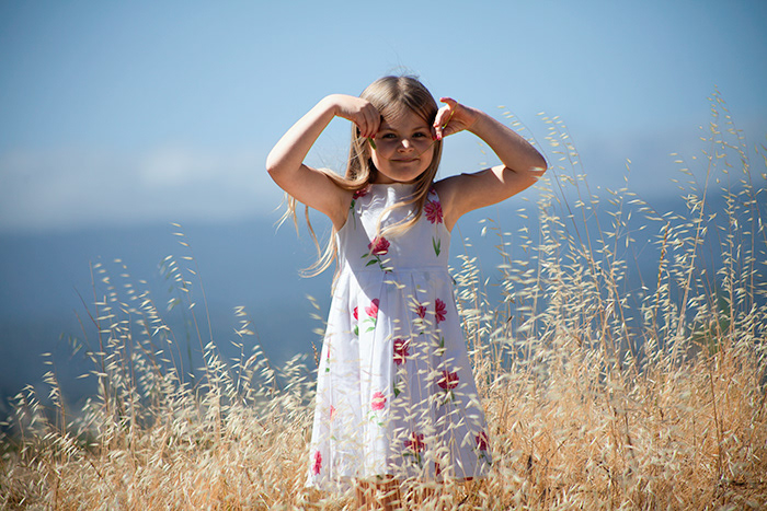 Lifestyle portrait of young girl in golden field smiling
