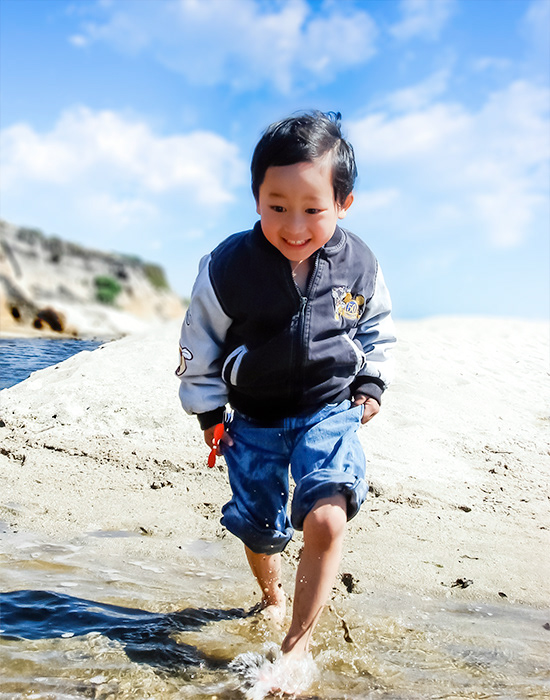 Photograph of smiling young boy running at beach