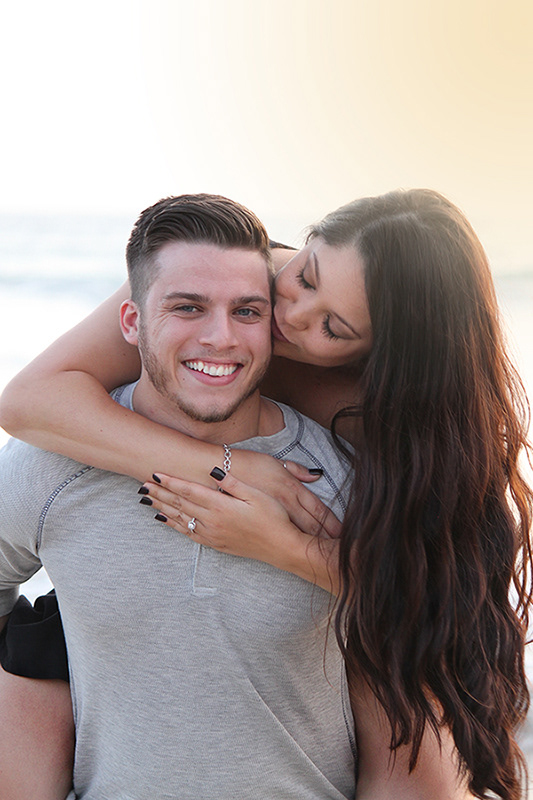 engagement photo of couple embracing and kissing at beach