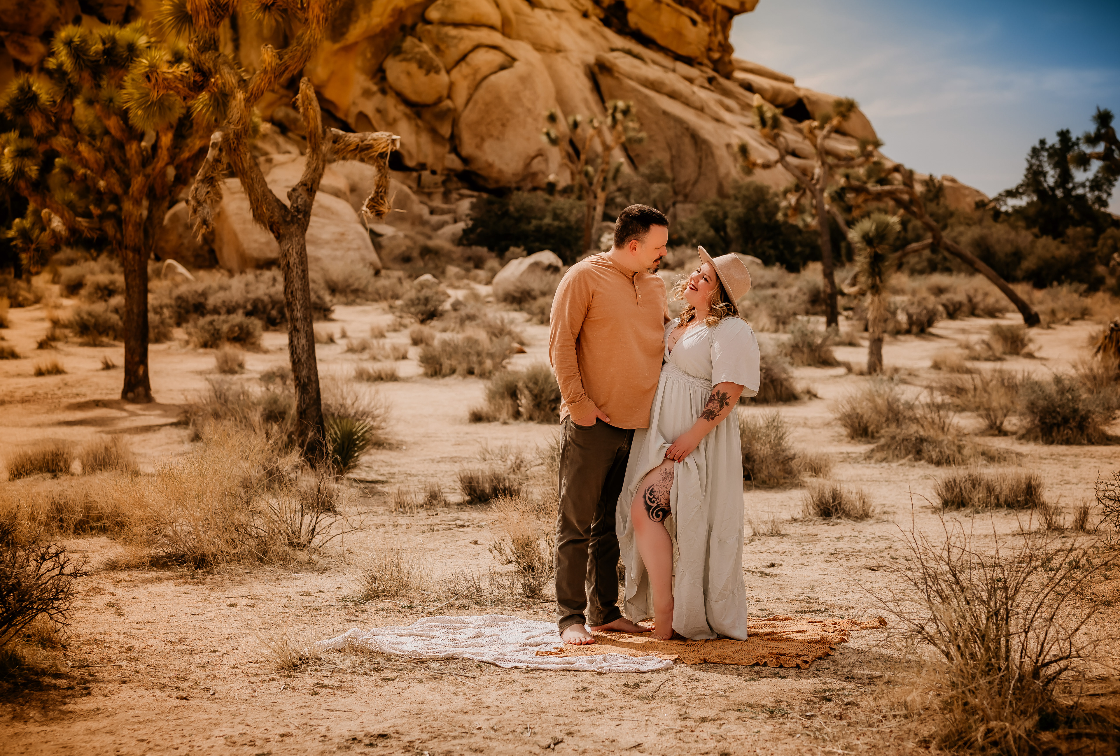A couple standing next to each other. Looking lovingly into each others eyes. Photograph taken by Hearts and Arrow Photography. Family session in Joshua Tree, California