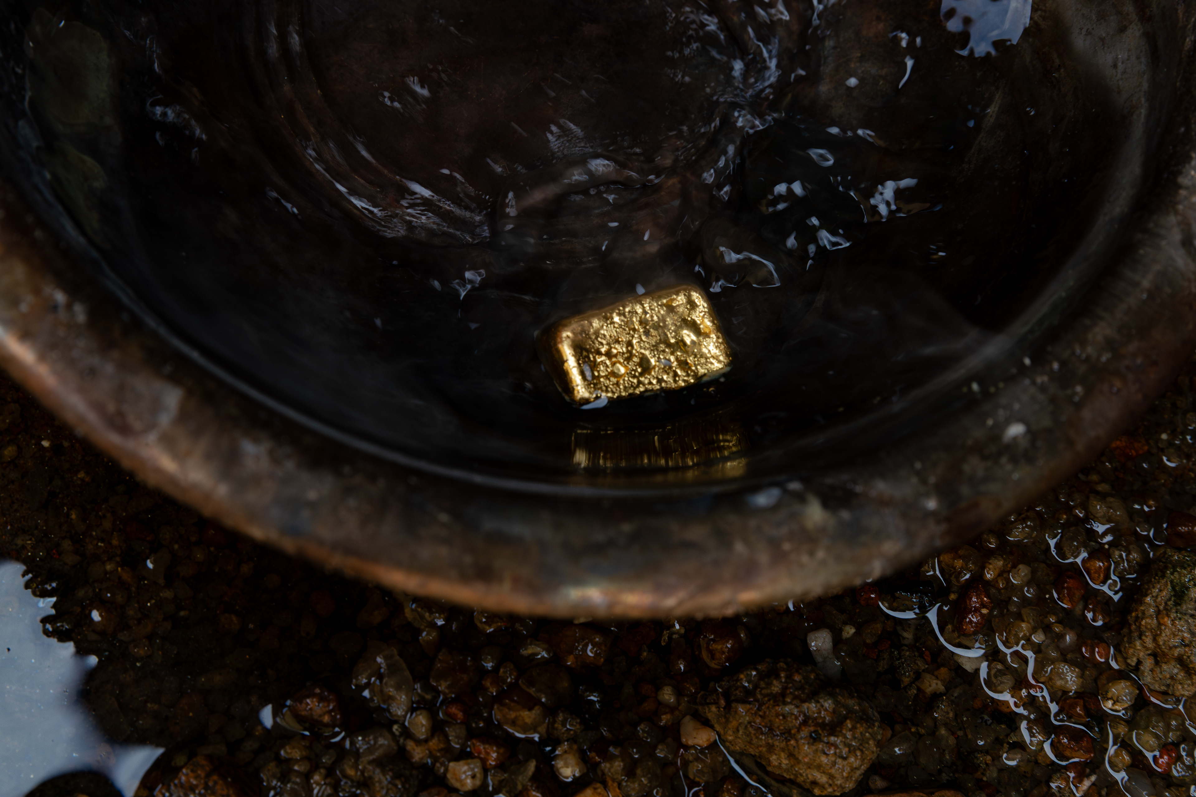 The final result of the process: a gold bar resting in water after casting and cooling.