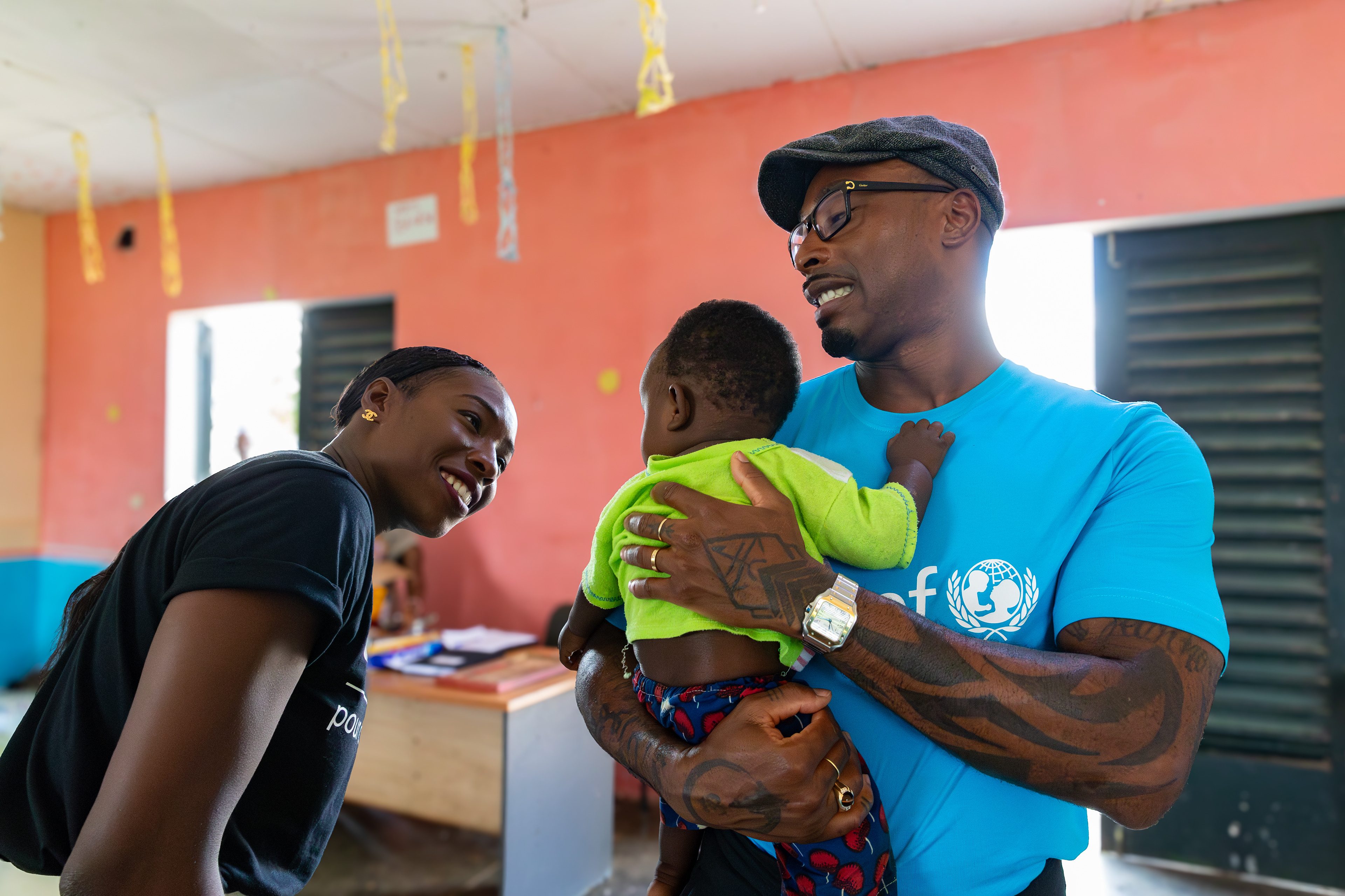 On 15th October 2024, at the daycare in Guédikpo, South-West Côte d’Ivoire, Jeff Demps, husband of UNICEF Ambassador Murielle Ahouré Demps, holds 7-month-old Mael, while Murielle stands by his side during their visit as part of the Girl Power project. Captured by Miléquêm Diarassouba, Photojournalist West Africa.