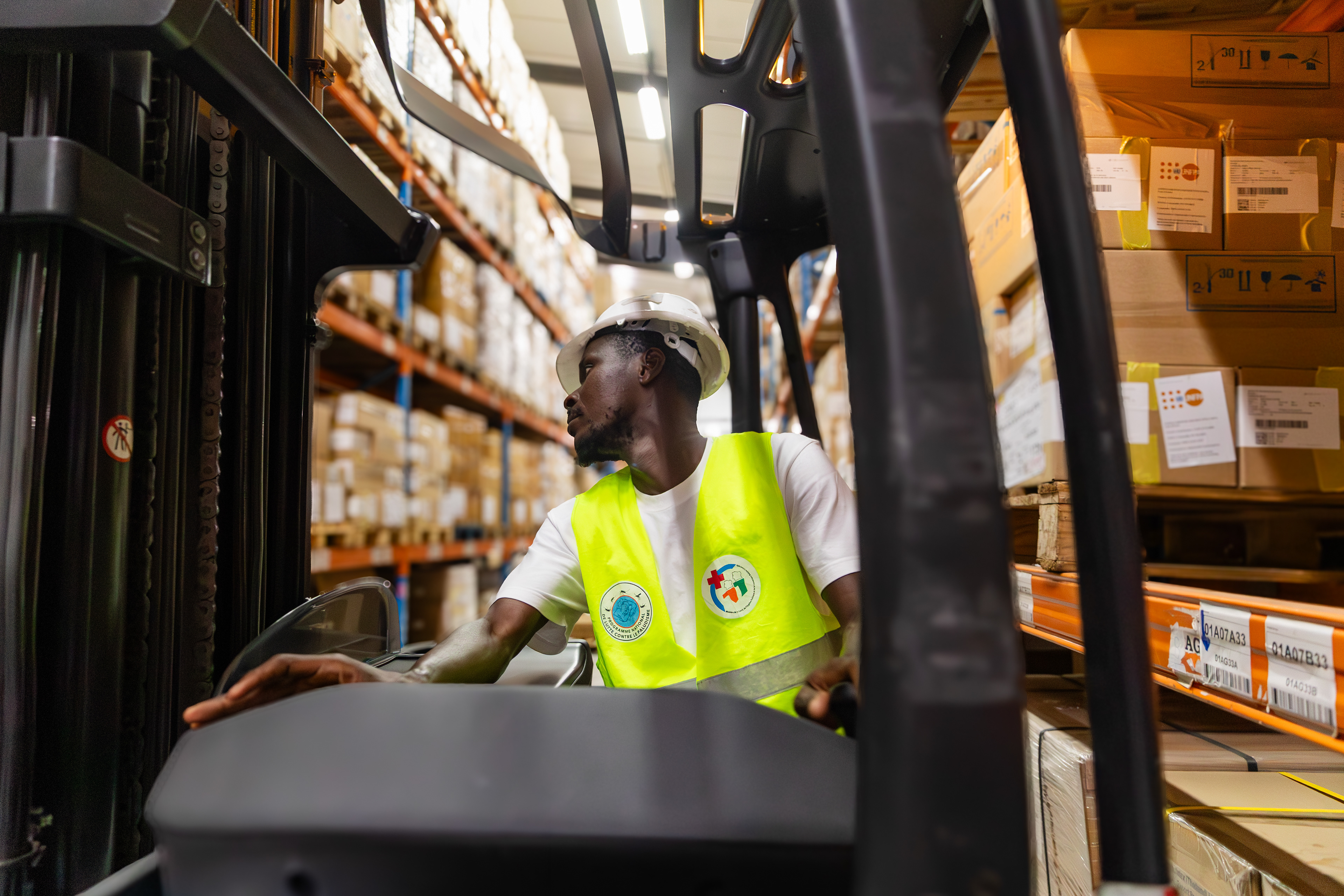 On 8 September 2025 in Abidjan, Benjamin, a forklift operator at the Nouvelle Pharmacie de la Santé Publique (NPSP), is pictured at the organization’s central warehouse. His work ensures the safe handling and movement of essential health commodities, contributing to the continuous flow of medicines and supplies to health facilities across Côte d’Ivoire.