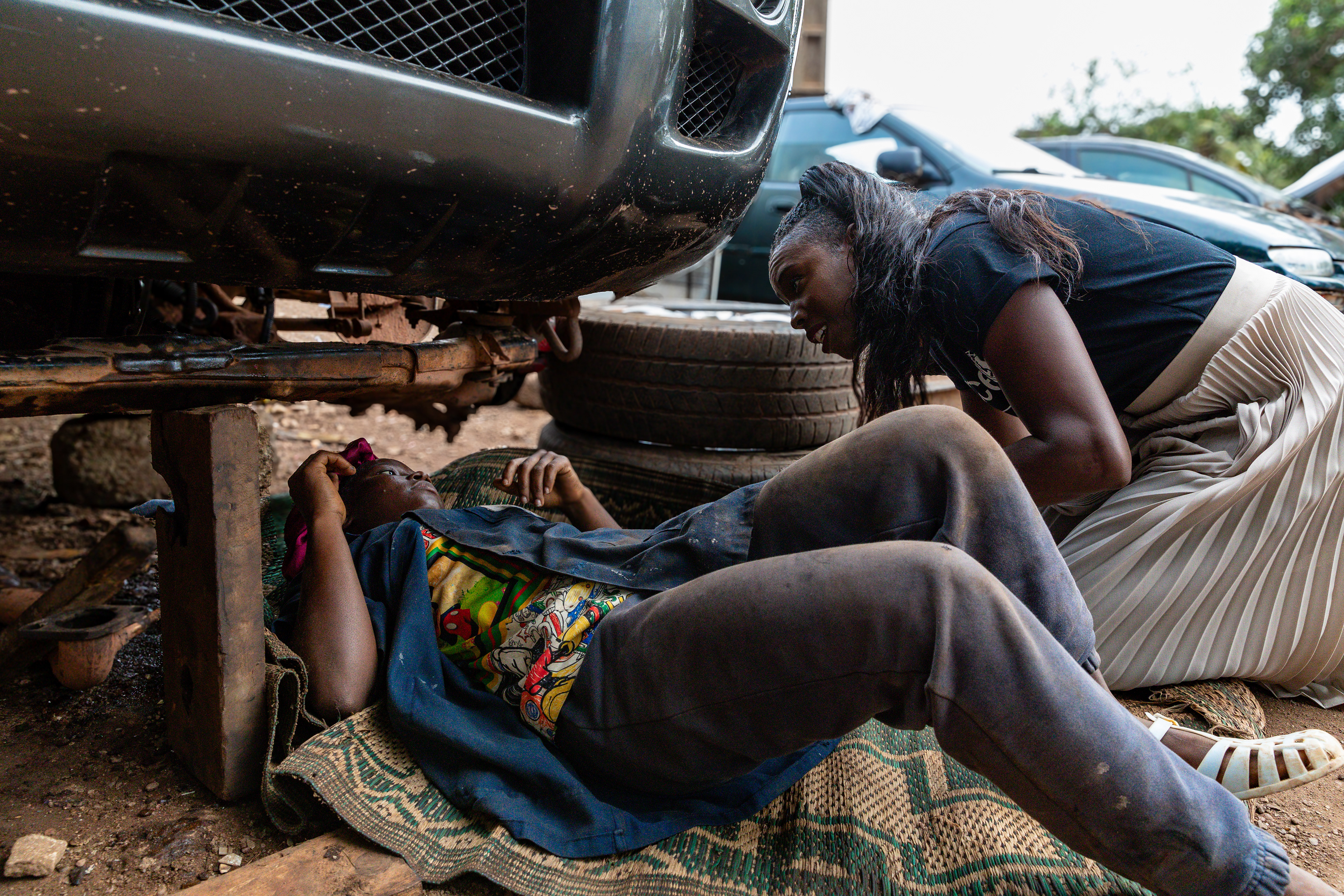 18-year-old Marie Grace works underneath a car while UNICEF Ambassador Murielle Ahouré Demps kneels beside her during a visit to San Pedro, South-West Côte d’Ivoire, on 14th October 2024.Captured by Miléquêm Diarassouba, Photojournalist West Africa.