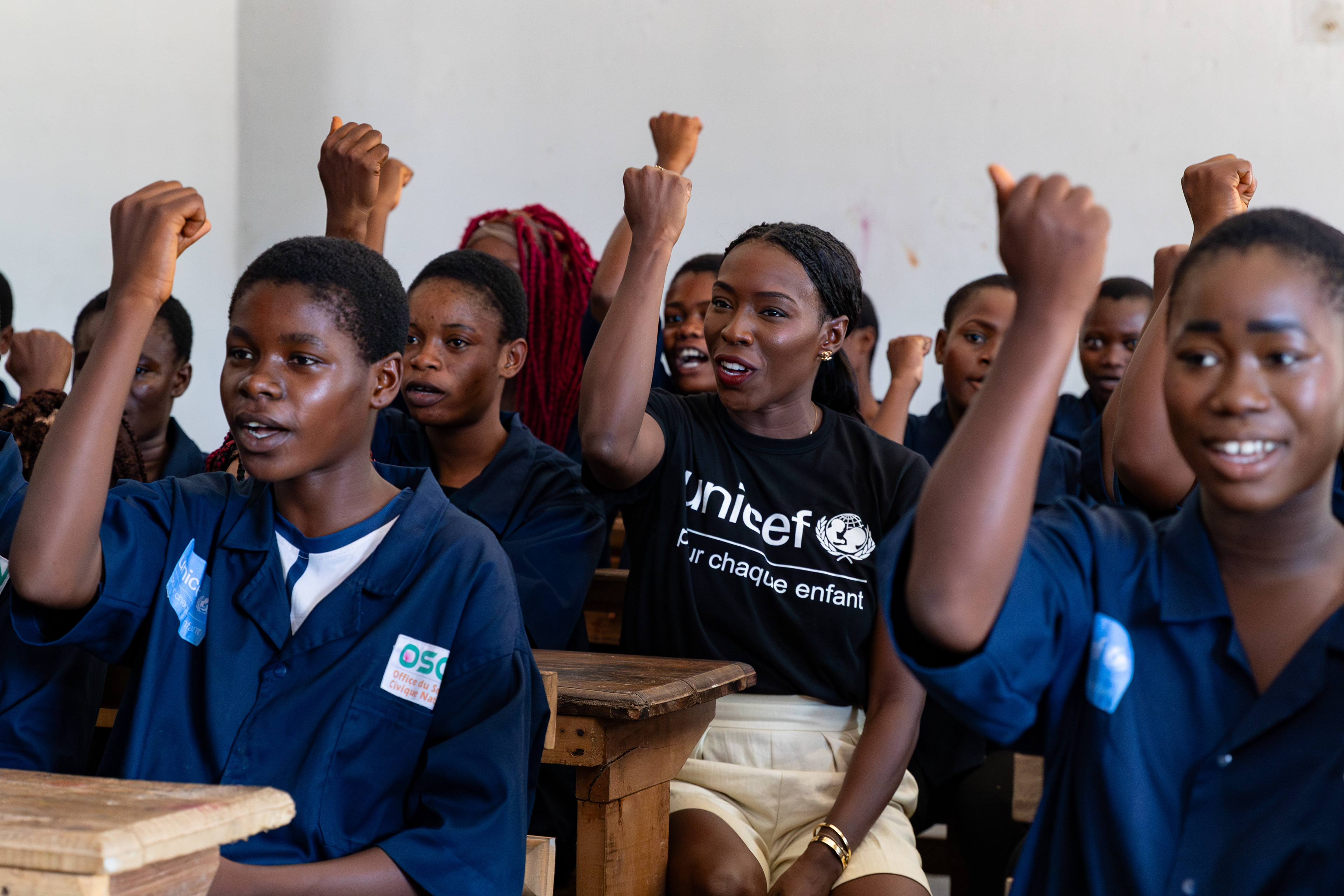UNICEF Ambassador Murielle Ahouré Demps joins the girls in the classroom at the Centre Civique d’Action pour le Développement in Guédikpo, South-West Côte d’Ivoire, on 15th October 2024, as they all raise their arms in the empowering Girl Power gesture. Captured by Miléquêm Diarassouba, Photojournalist West Africa.