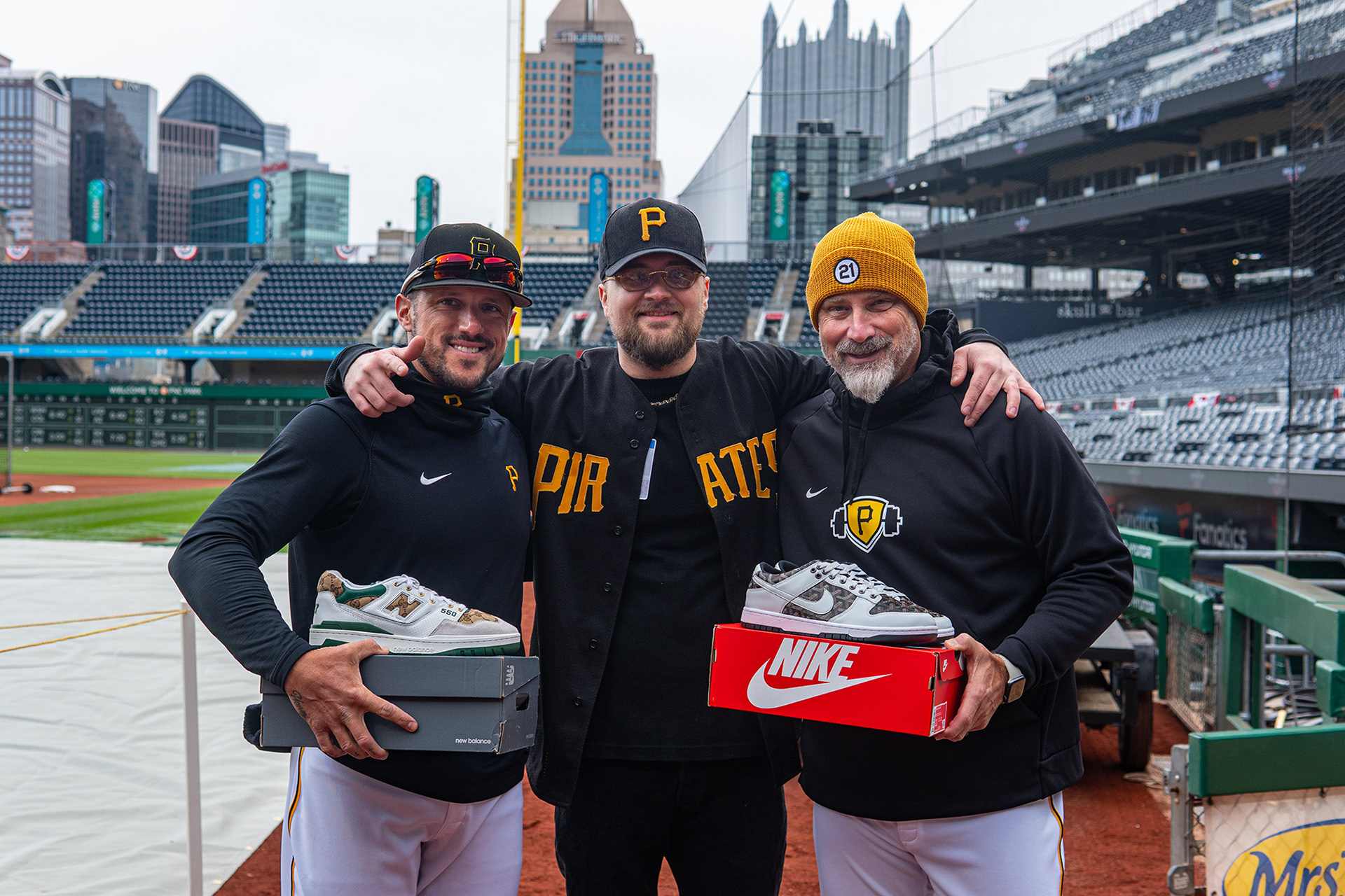 Jordan Comadena, Jesse Woods, and Derek Shelton pose for a photo with custom shoes they received from Jesse Woods. On Opening Day down at PNC Park standing on-field.