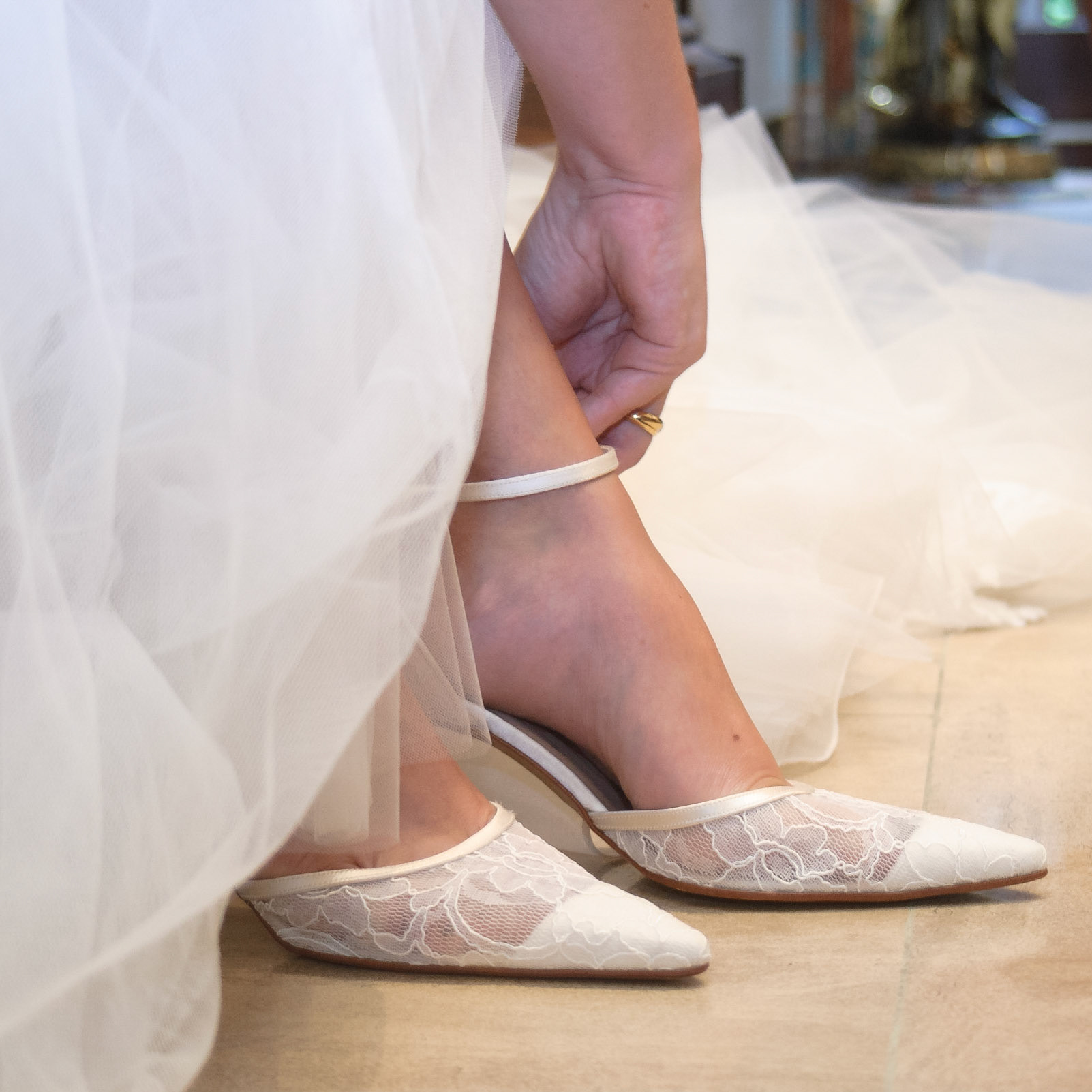 Closeup of a bride,who's closing her white wedding shoes while preparing