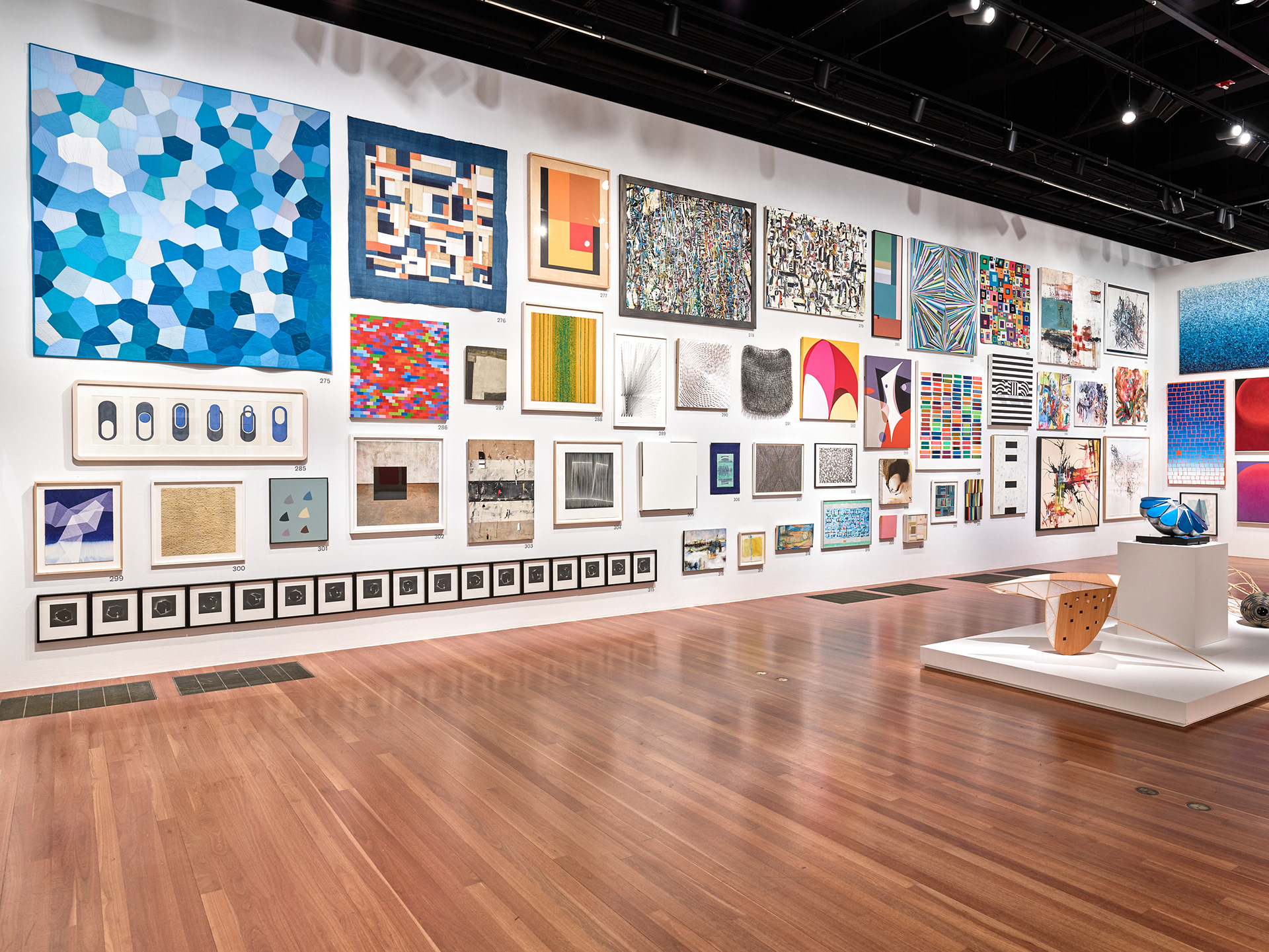 Salon-style installation balancing artwork of varied scale within a thematic gallery.