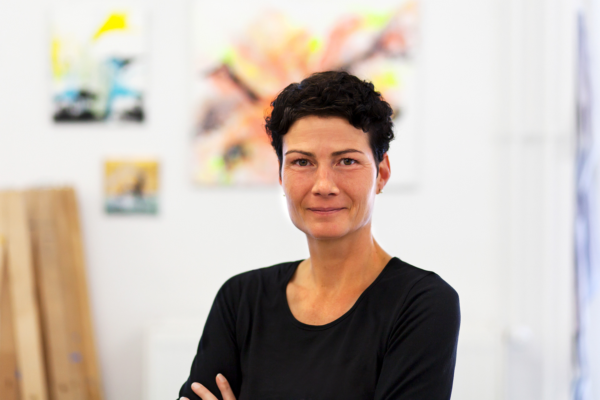 Portraitaufnahme von der Künstlerin in ihrem Atelier. Hintergrund in der Unschärfe.