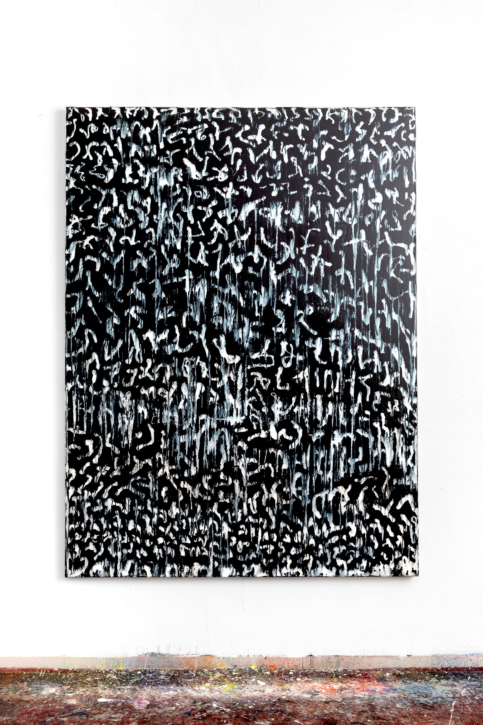Monochromes abstraktes Bild an der Wand hängend mit Boden sichtbar, der Farbschichten überzogen ist.