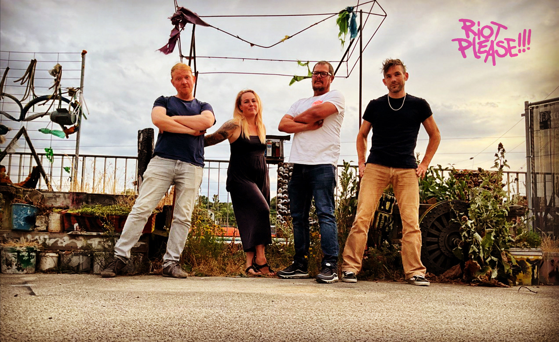 Gruppenfoto der Band Riot Please in Straßenhinterhof-Szenerie.