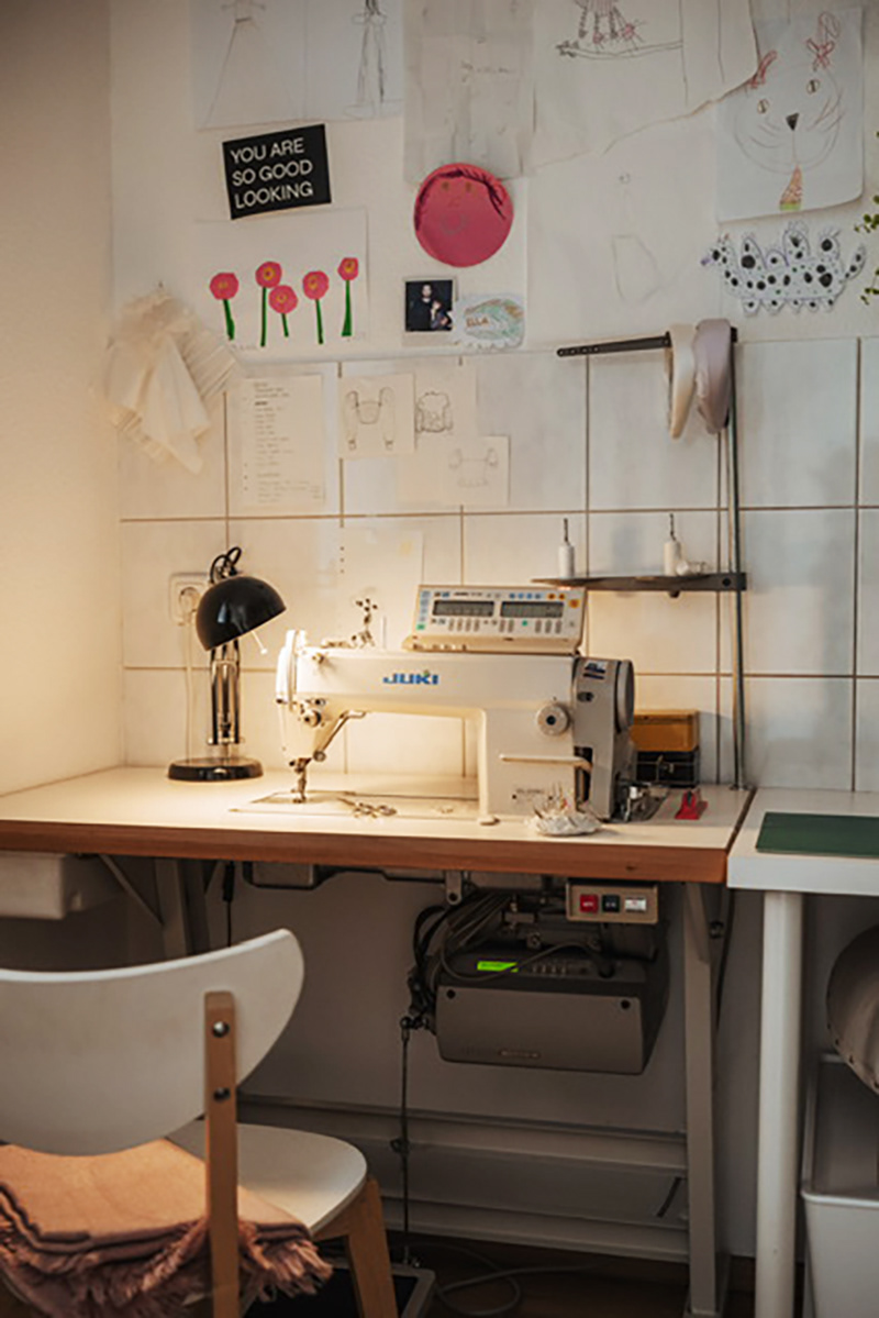 Blick auf den Nähtisch mit Nähmaschine, Lampe und Inspirationsbilder an die Wand gepinnt.