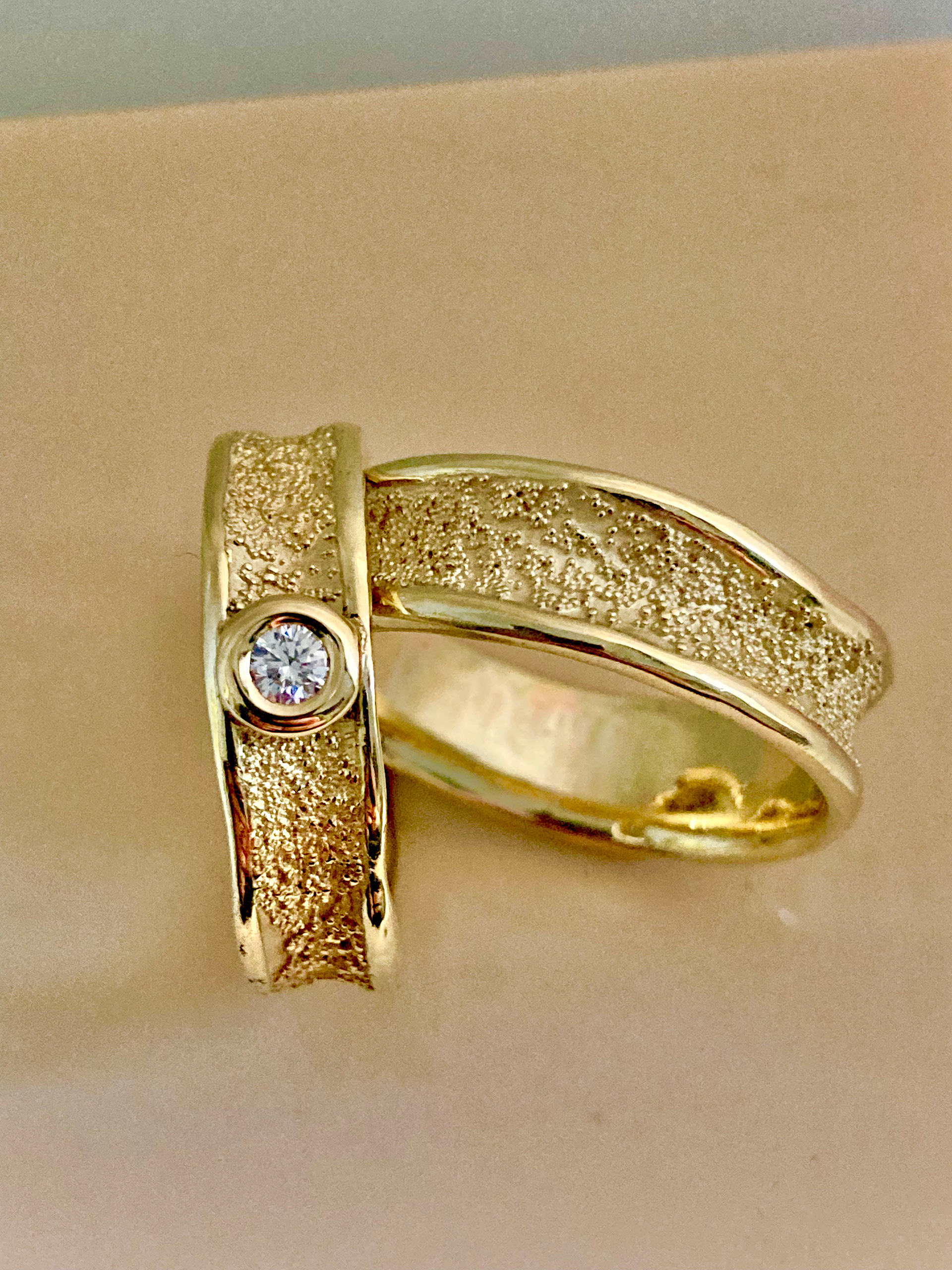 Nahaufnahme zweier Goldringe ineinander aufgestellt. Einer mit weißem Stein eingefasst.