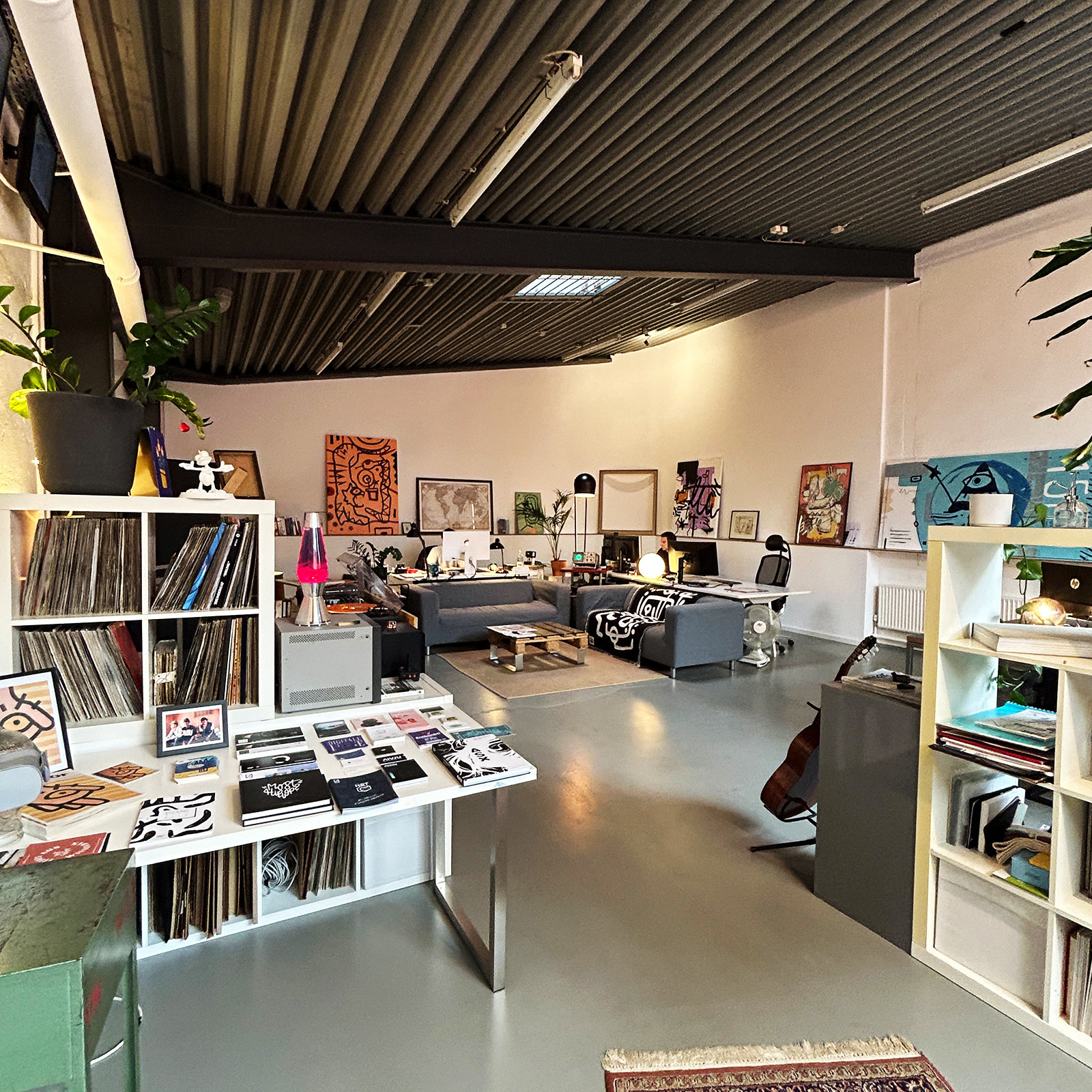 Innenraumansicht vom gemeinsamen Arbeitsraum. Tische, Couches, Ablageflächen und Wanddeko zu sehen.