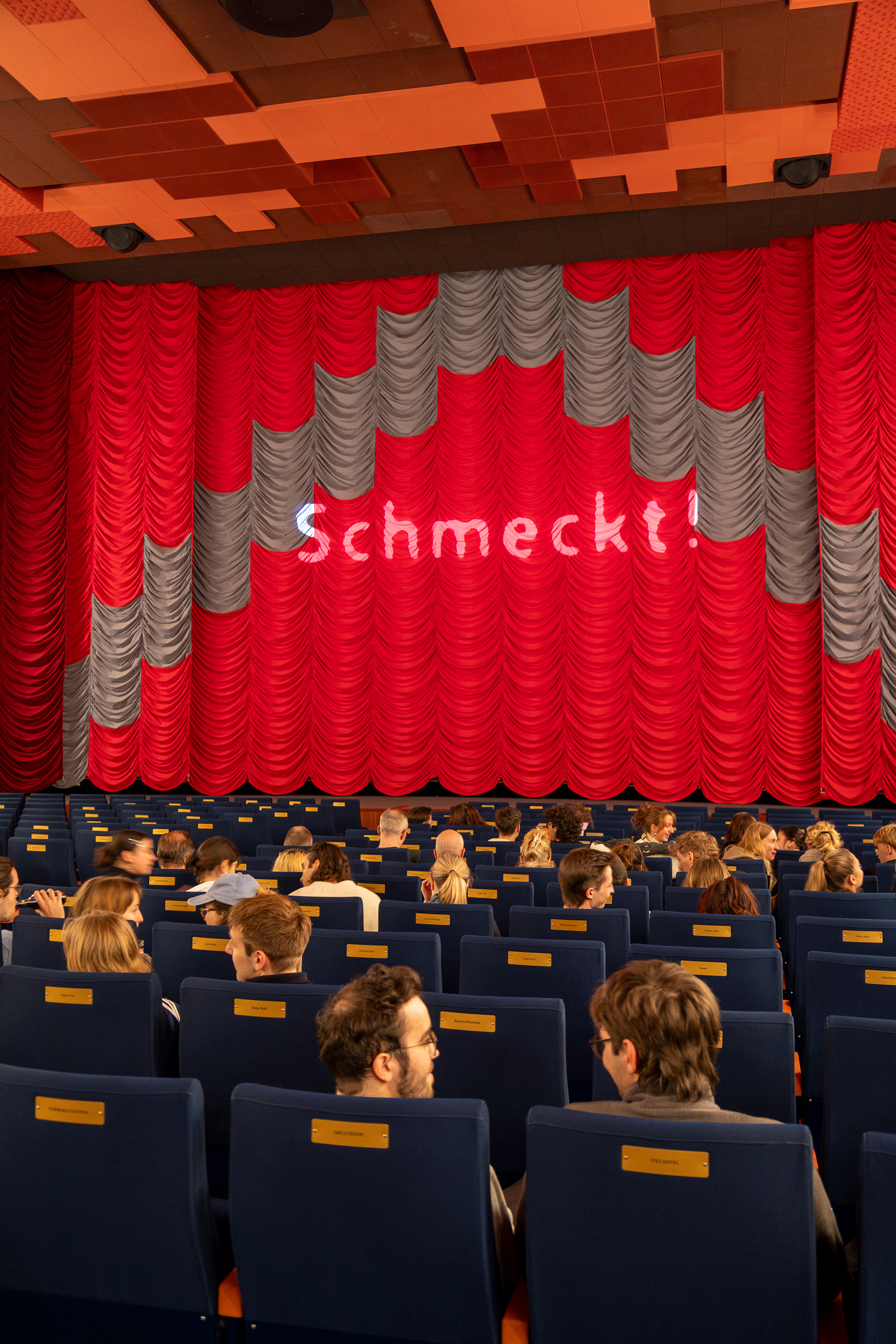 Der Kinosaal, auf den roten Vorhang das Schmeckt!-Logo projiziert