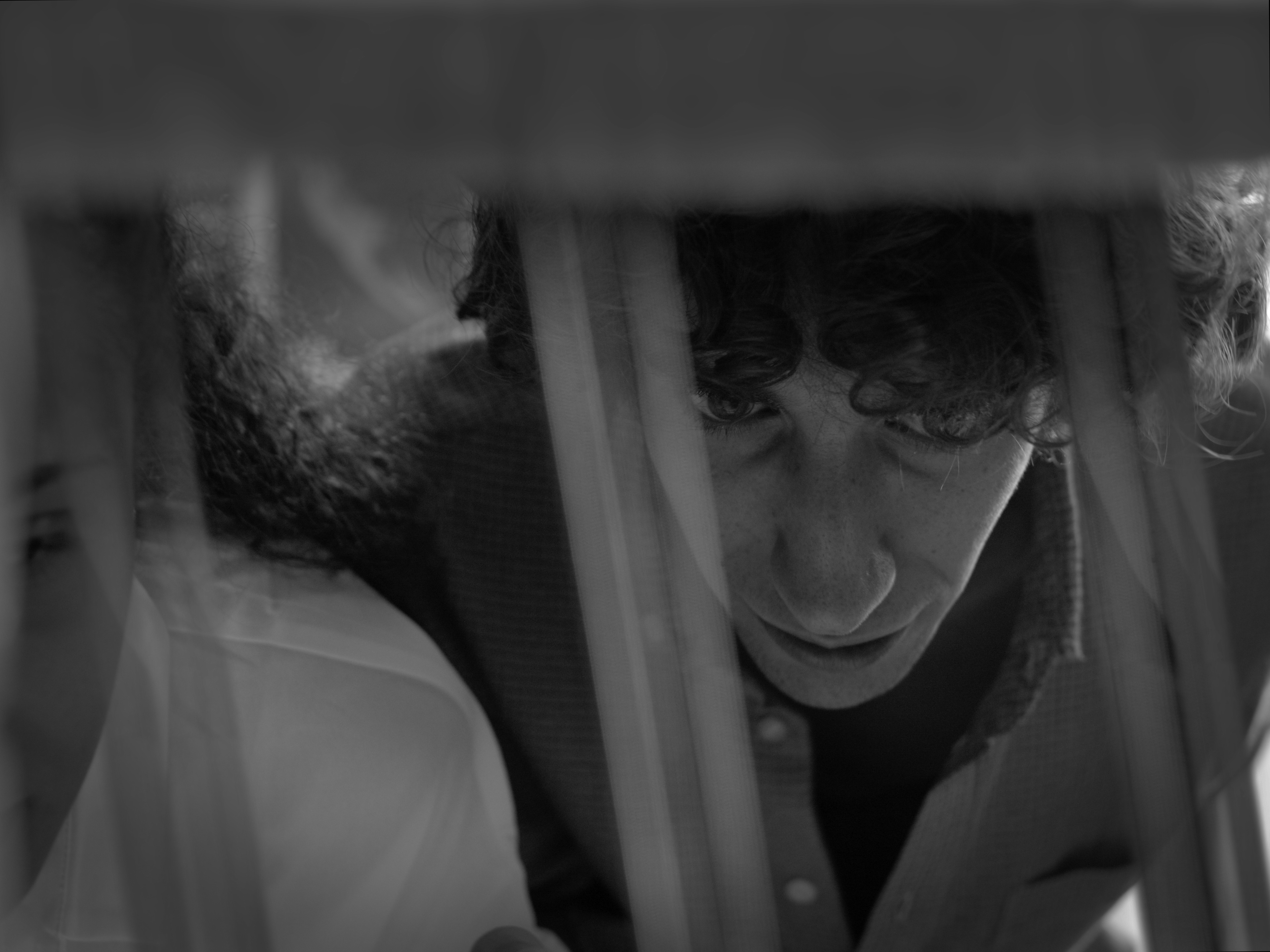 Ein Filmstill aus dem Film "Il Non Pianista", das Gesicht des Protagonisten ist groß, hinter verschwommenen Stangen zu sehen.