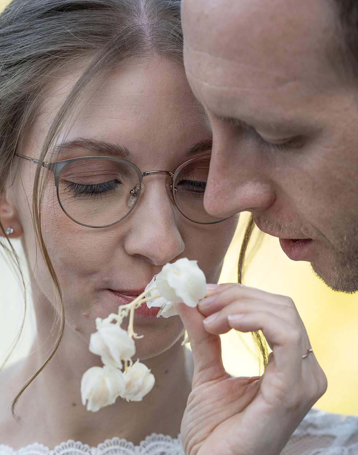 Brautpaar in ruhigem Moment, das an einer Blume in der Allgäuer Natur riecht. Fotografiert von Flo Steinweg Photography