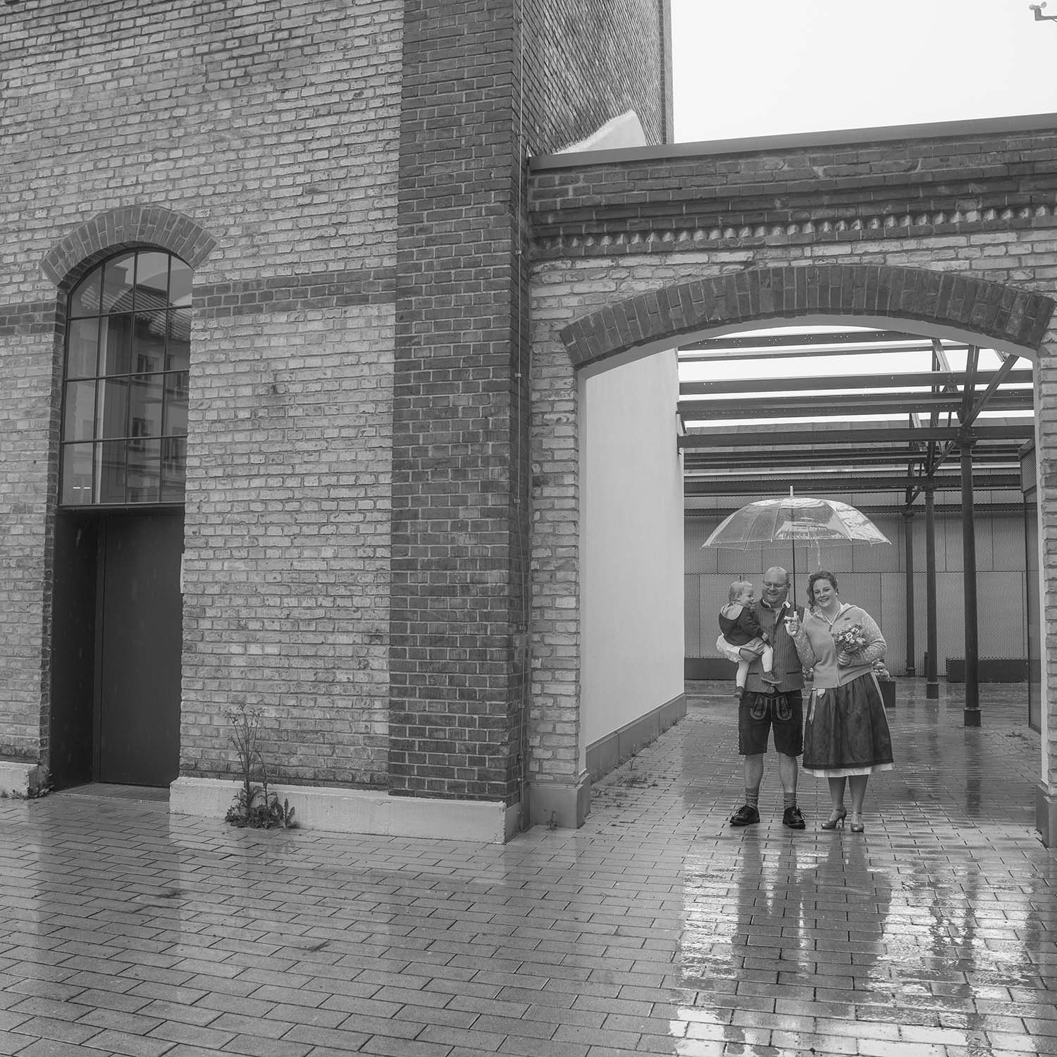 Das Brautpaar mit Kind geschützt unter dem Schirm, der Fotograf im Regen :-)