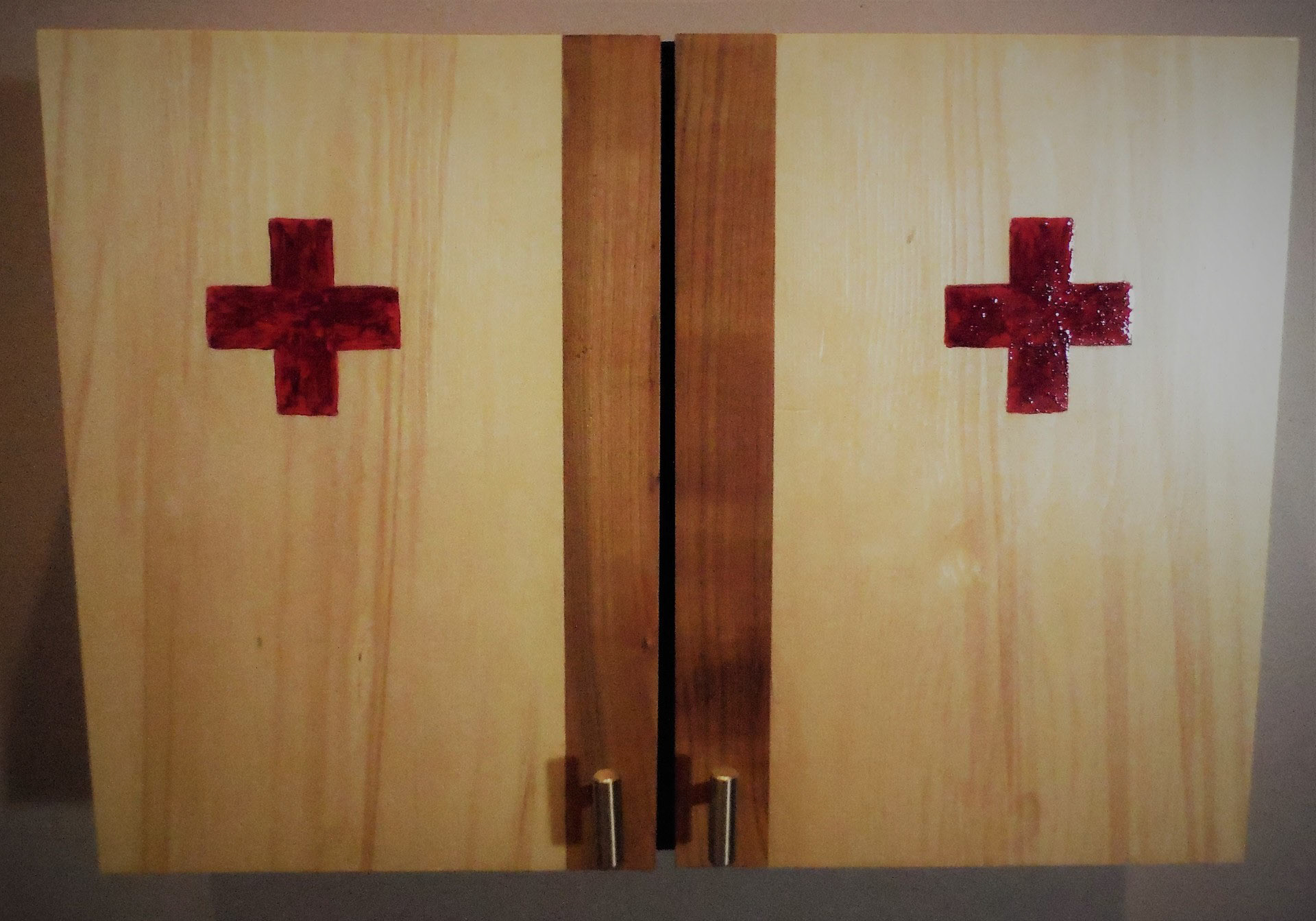 Moch pine first aid cabinet with hinged doors and one two shelves supporting 5 pre WWII rusted tin cans that have been opened by methods involving a knife as opposed to a can opener suggesting urgency. The cans symbolize the empty preparation needed when the nation accessed the first aid cabinet.