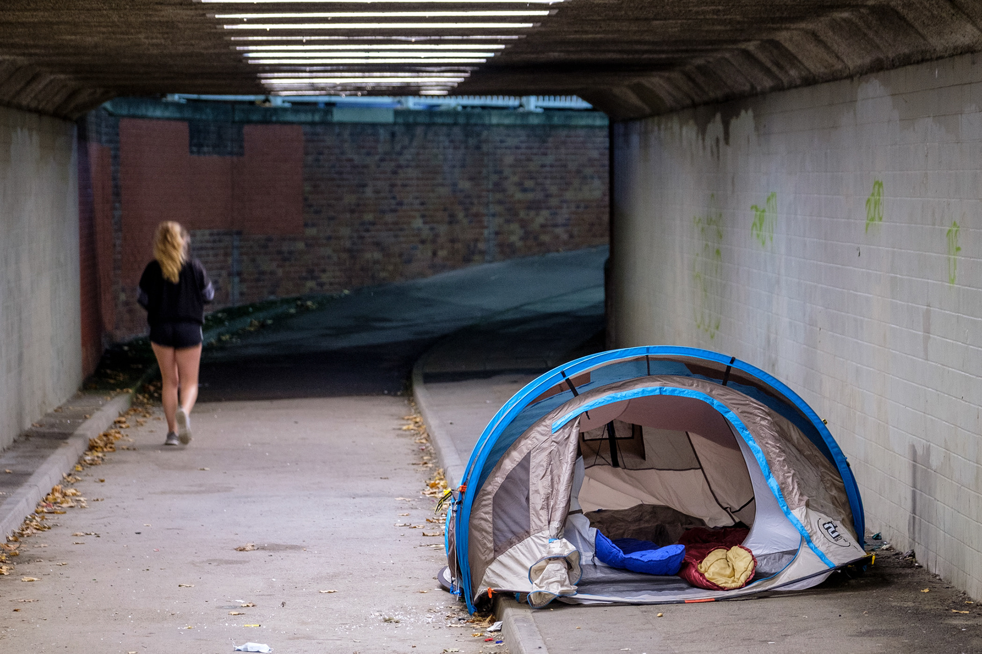 A tent and sleeping bags in a in an underpass used by a couple sleeping rough at night
