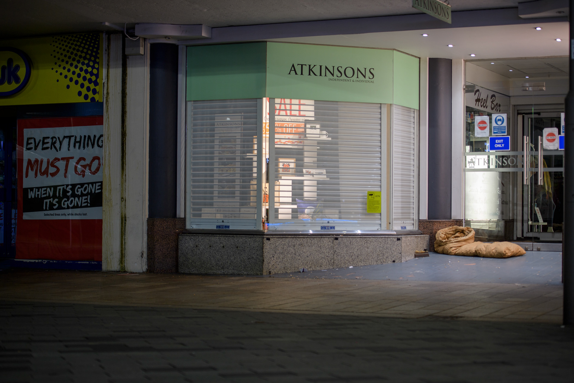 A sleeping bag in the doorway of a shop at night, Sheffield city centre, used by a person sleeping rough.
