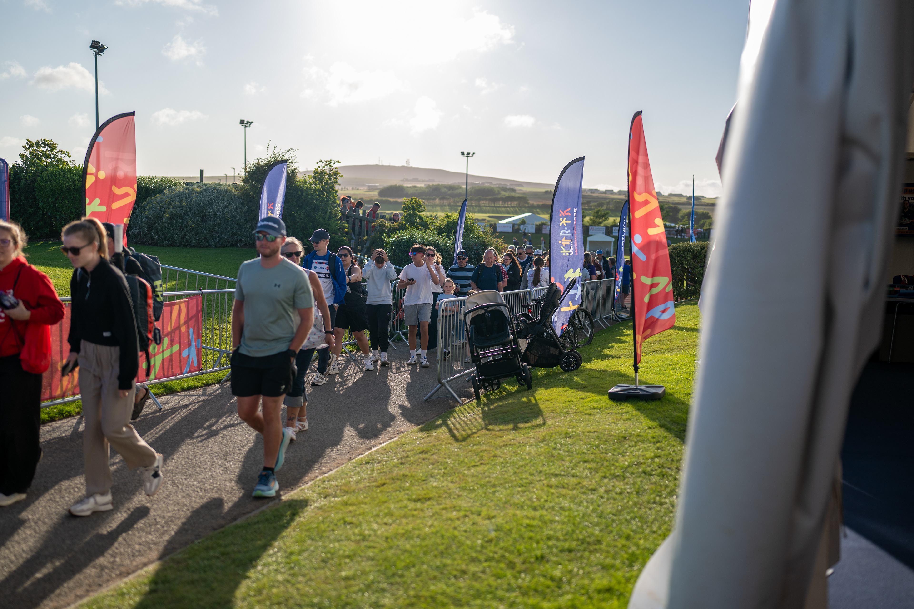 Residents and spectators  engaging with Orkney 2025 branding through flags and event dressing banners.