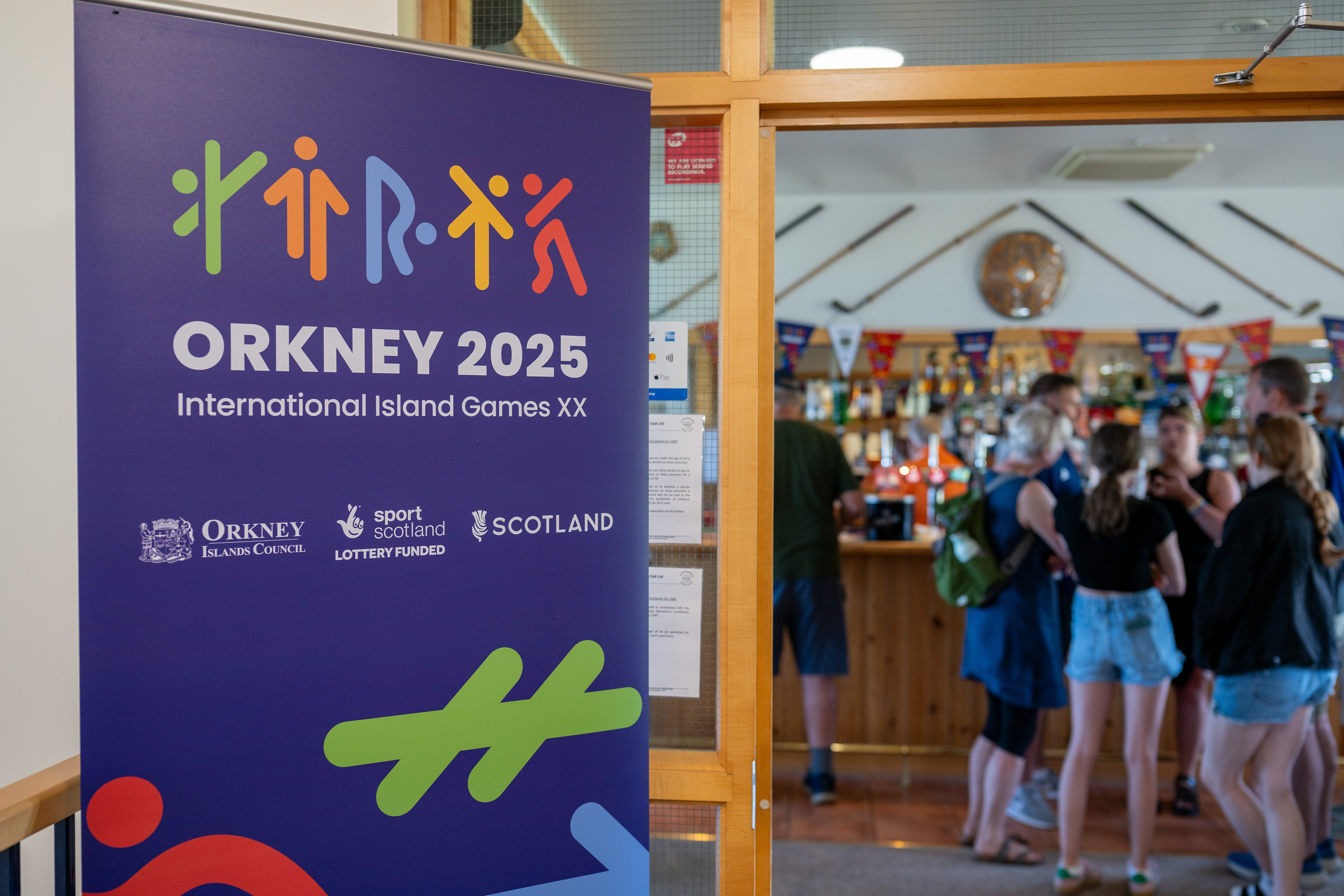 Local Orkney businesses displaying Orkney 2025 Island Games branded posters., pull-up banners and buntings