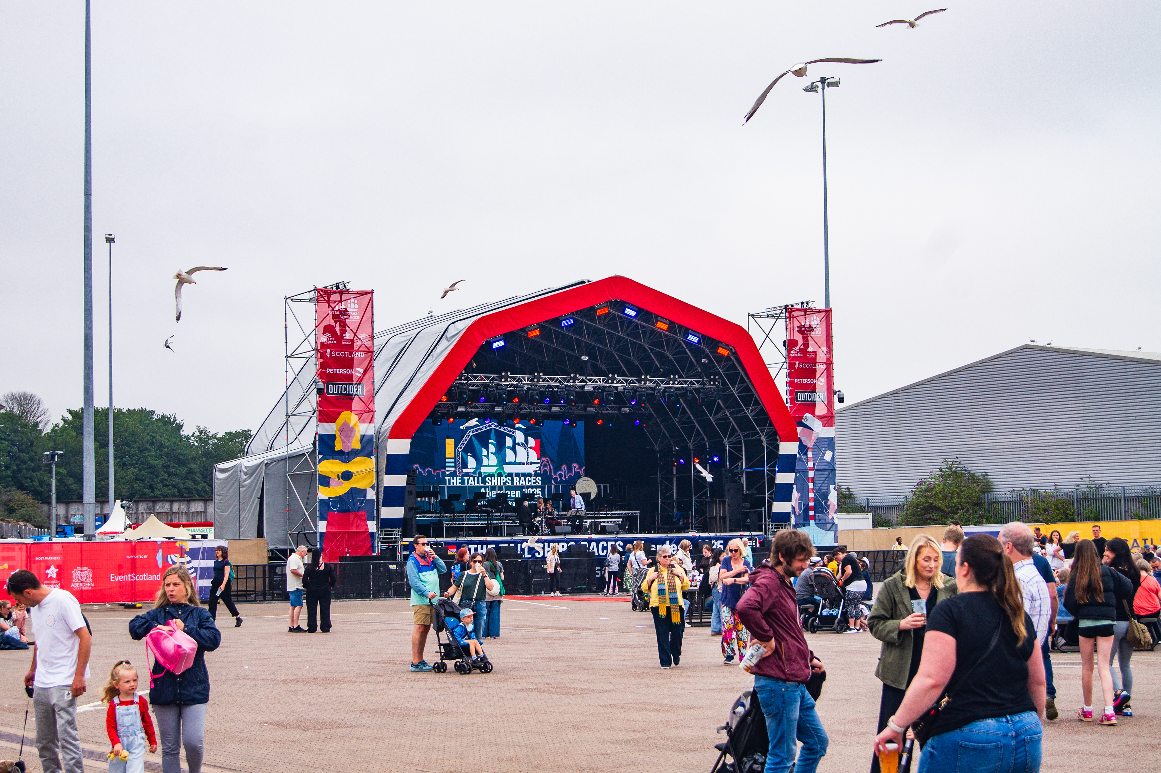 Festival-wide branding for the Tall Ships Race Aberdeen 2025 with venue dressing, stage graphics, bunting, and city centre applications.