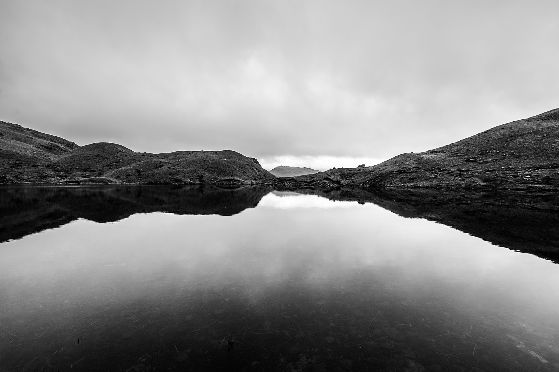 The mirror surface of Easedale Tarn in the Lake District reflects perfectly the crags at the top of Sourmilk Gill