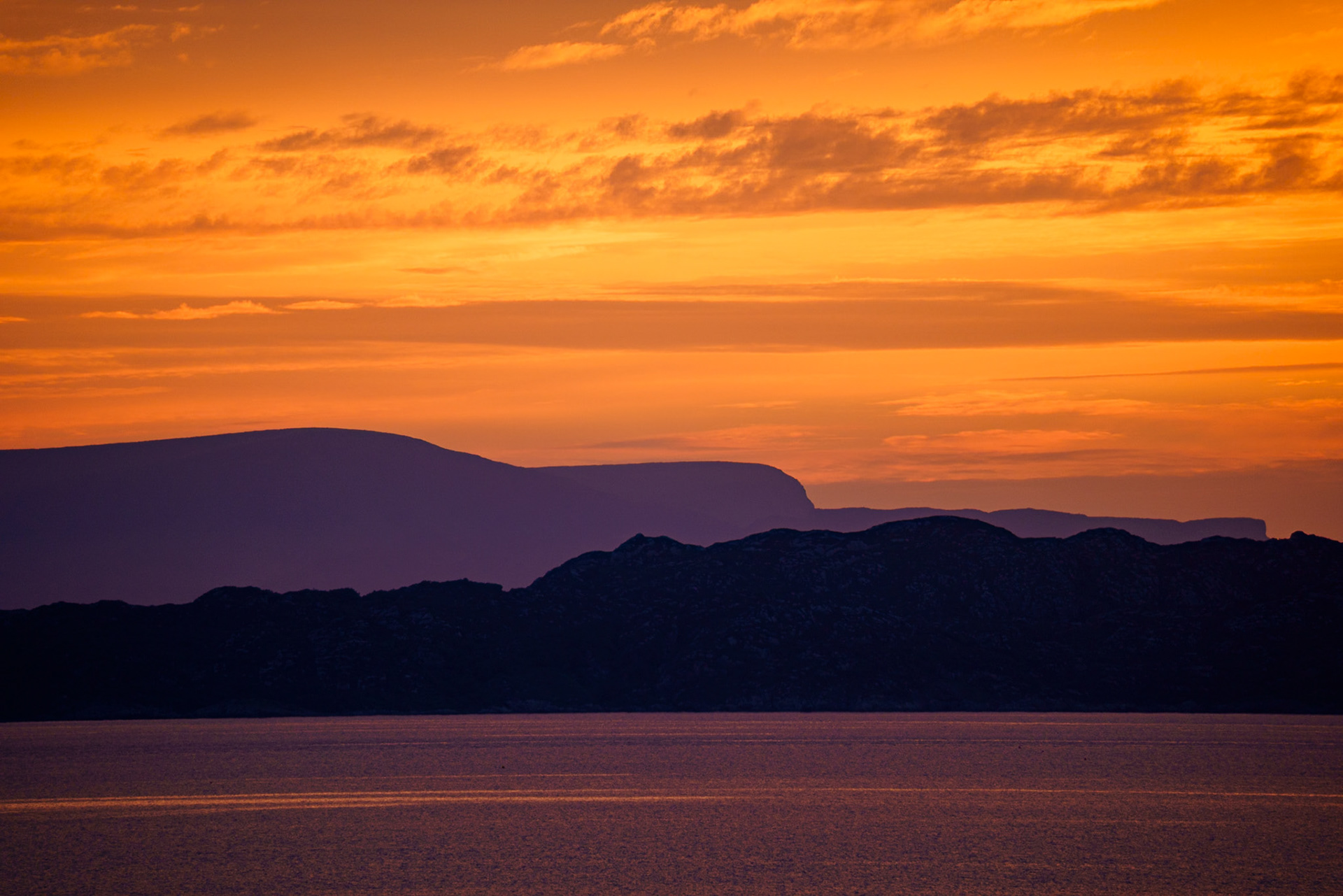 A golden sunset silhouettes the isles of Skye and Raasay on the west coast of Scotland.