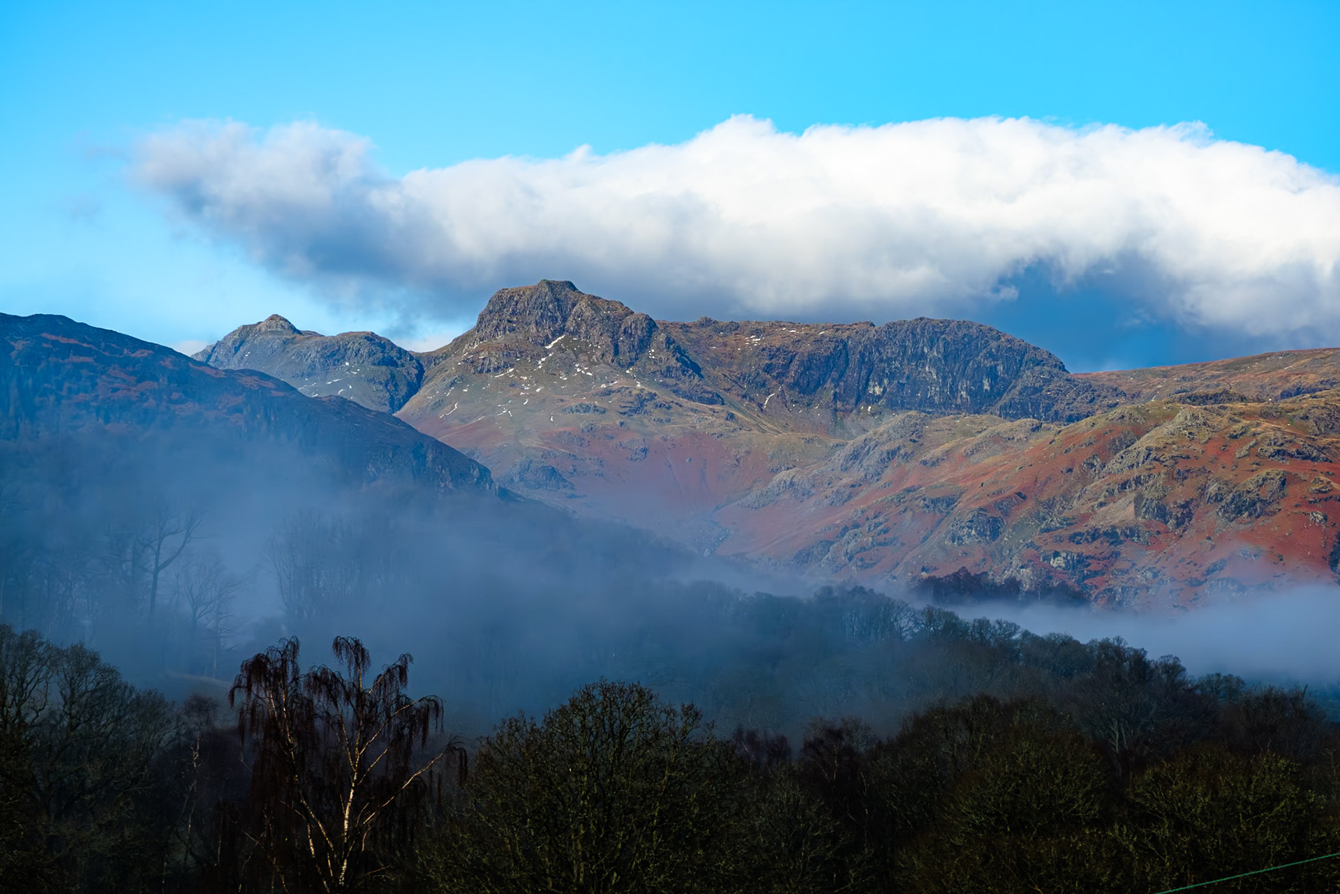 Early morning cloud and mist shrouds the Langdale Pikes, Cumbria.