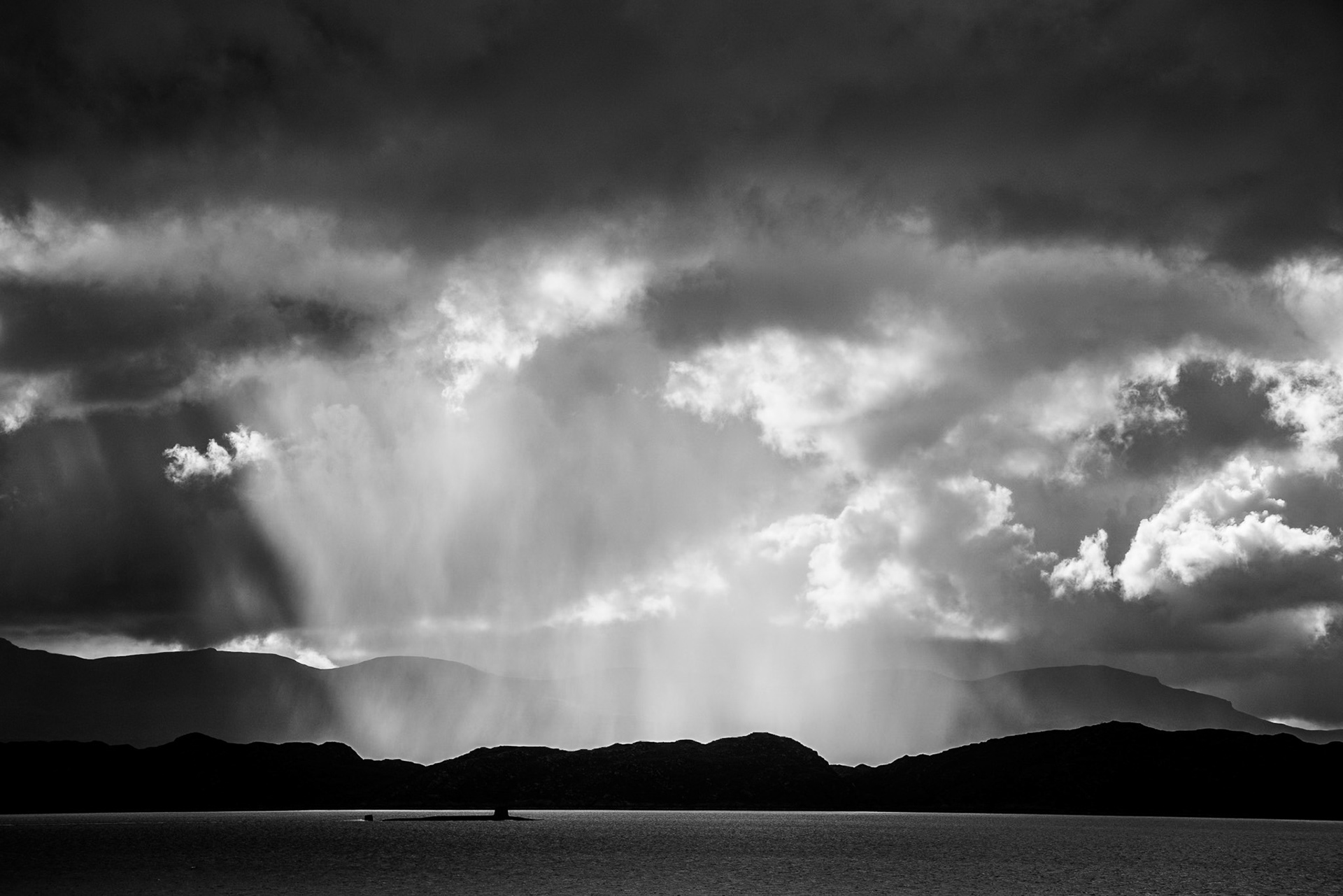 The Isle of Skye is shrouded in sweeping rain clouds and a dark brooding sky. A large submarine can be seen cruising across the black water on its way to sea.