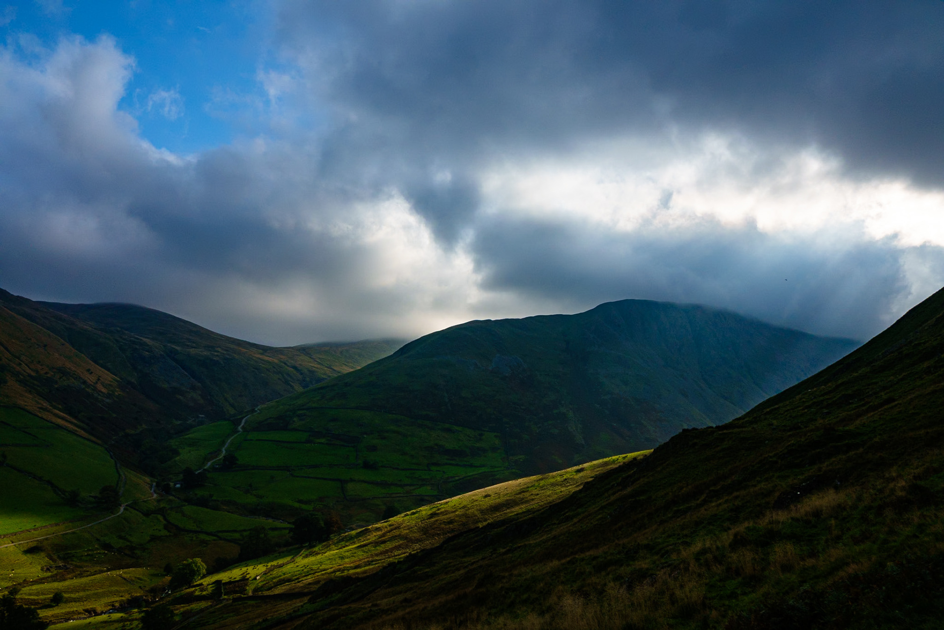 Shafts of light bursting through thick cloud to illuminate the slopes of Hartsop and Gray Crag.