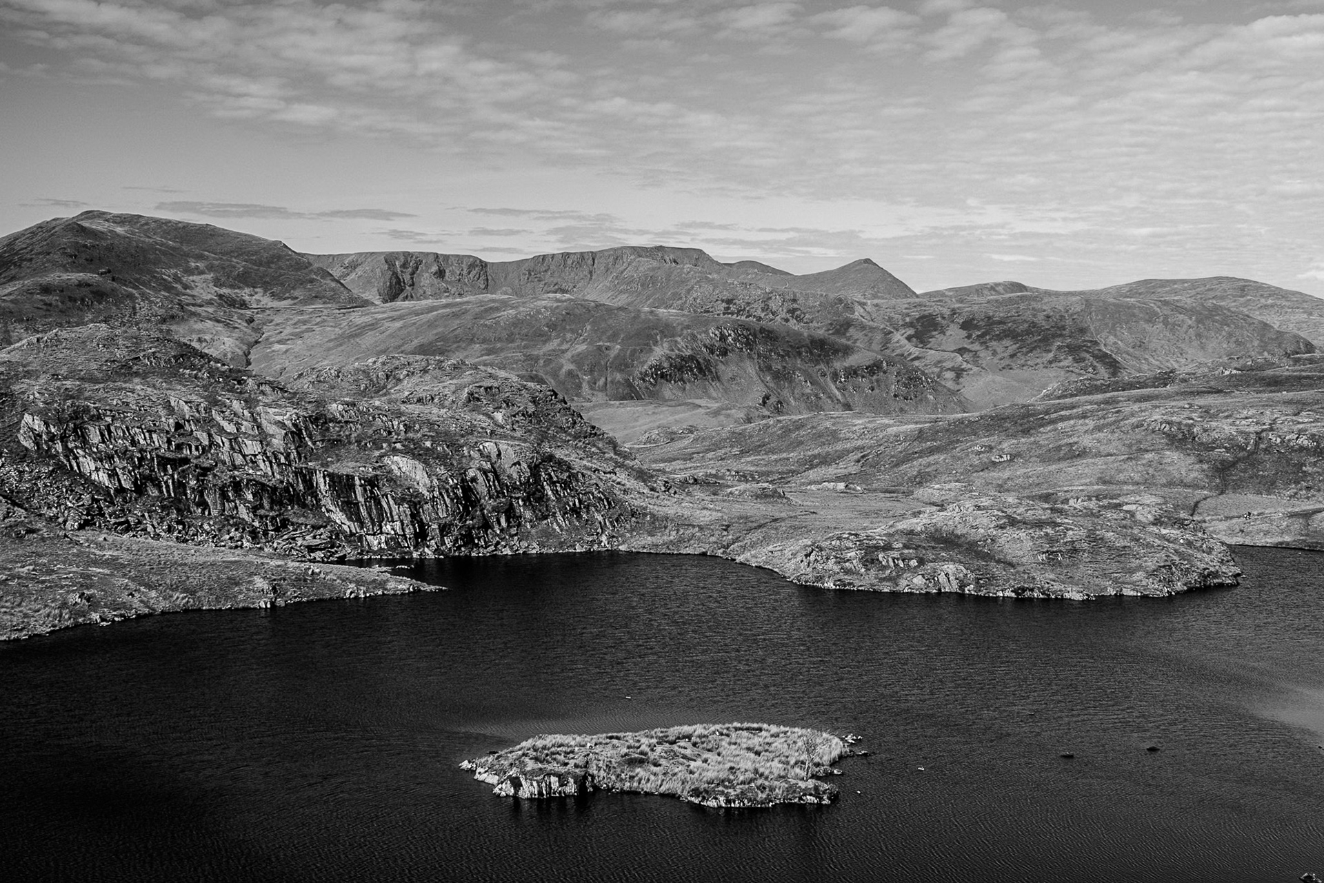A black and white image of Angle Tarn and The Helvellyn Mountains set under and almost cloudless summer sky.